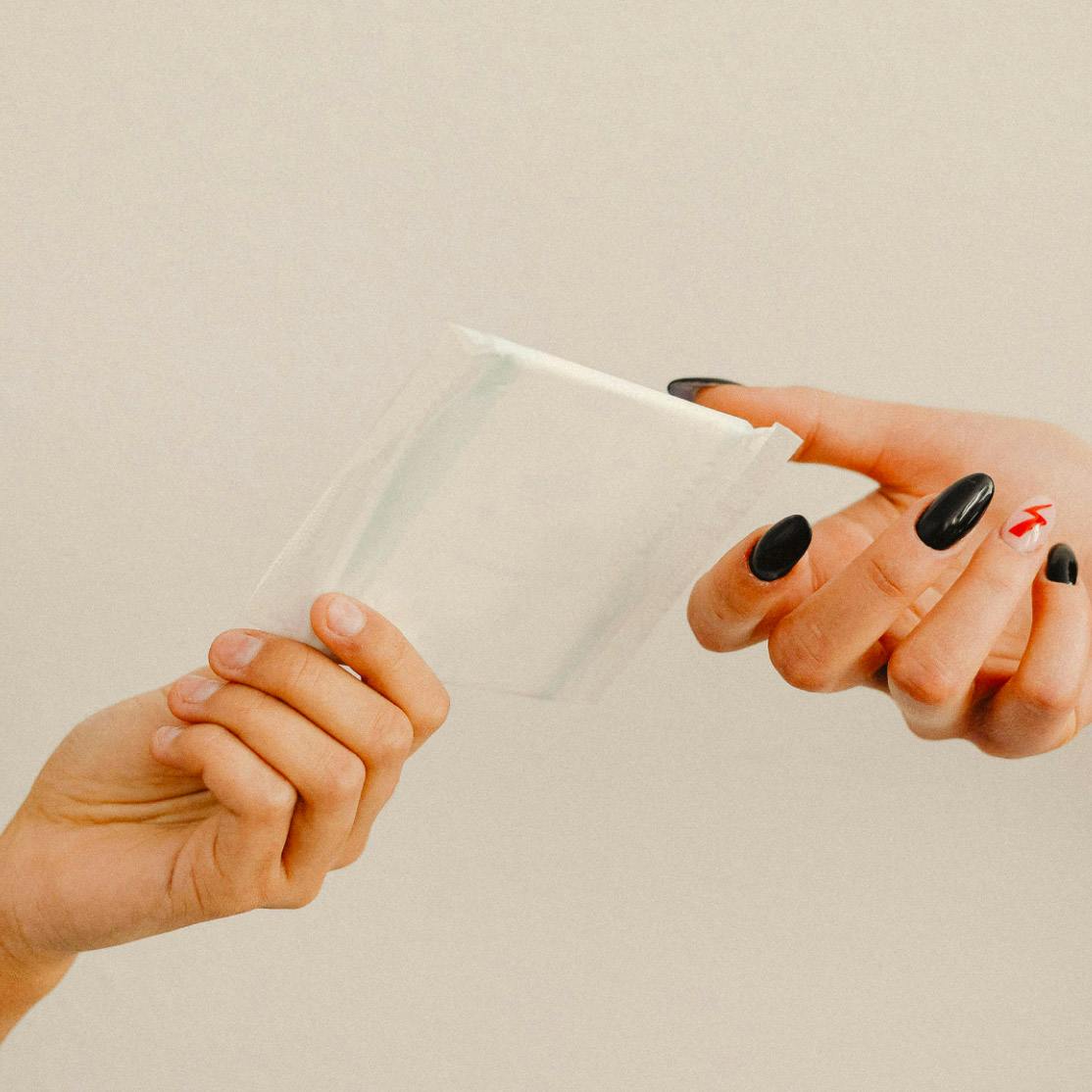two hands passing sanitary napkins