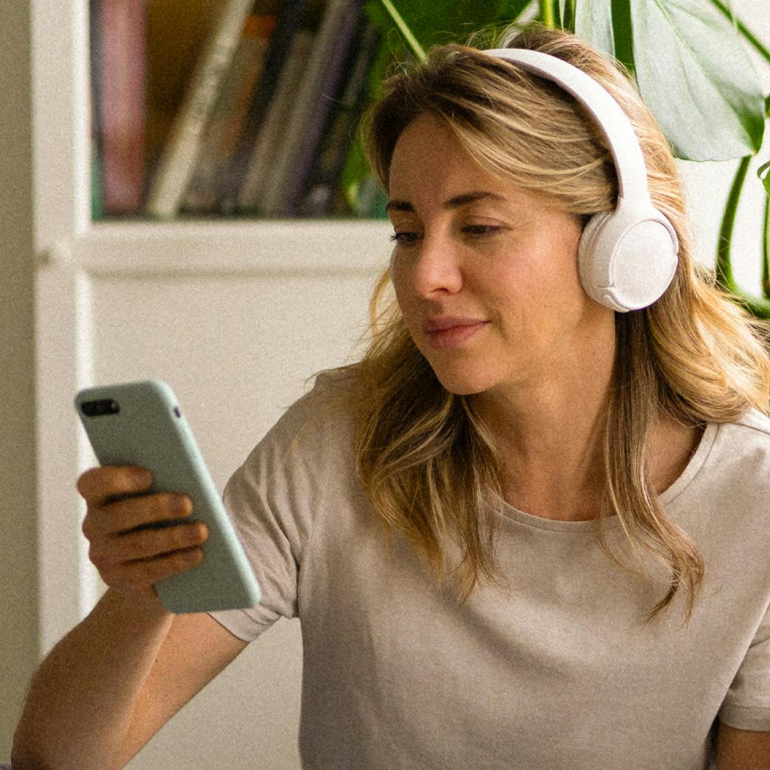 woman with headphones looking at her phone