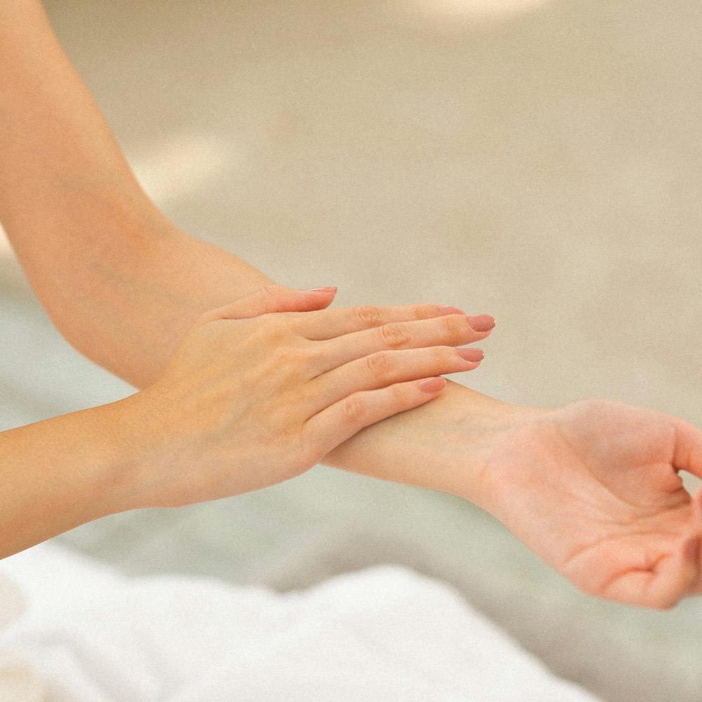 Close crop of woman's hand touching her inner arm