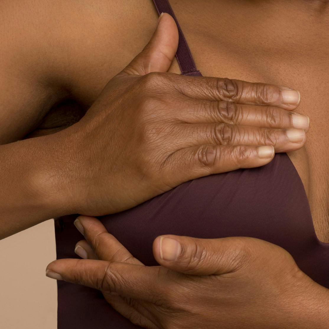 Close cropped image of woman cupping her breast in a bra