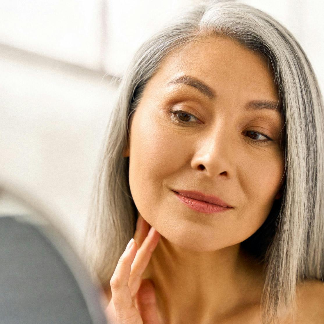 Image of woman looking at her face in the mirror