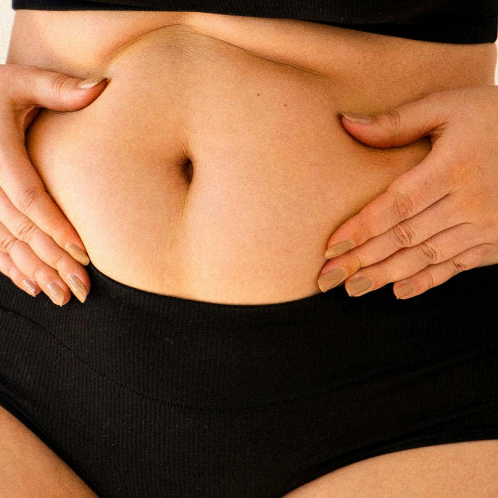 Image of a woman with hands on belly above underwear