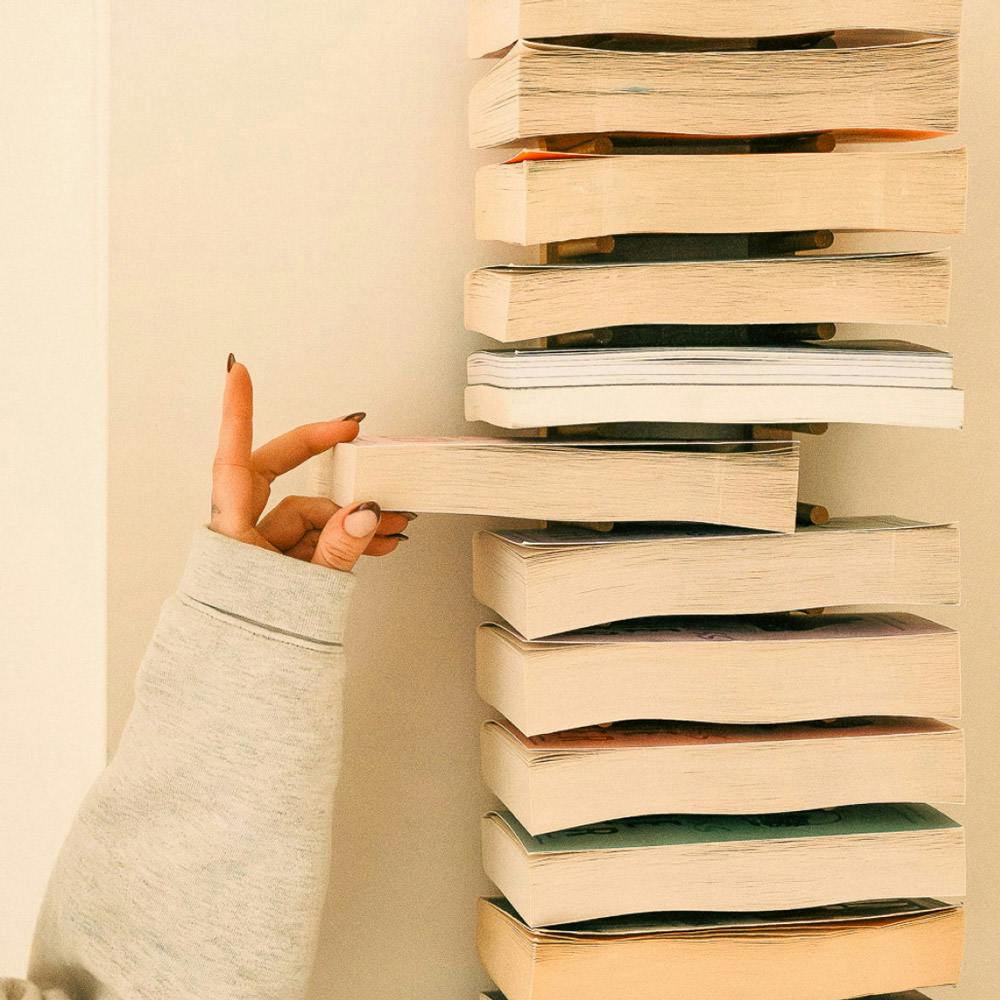 Image of a woman's hand reaching toward a bookcase