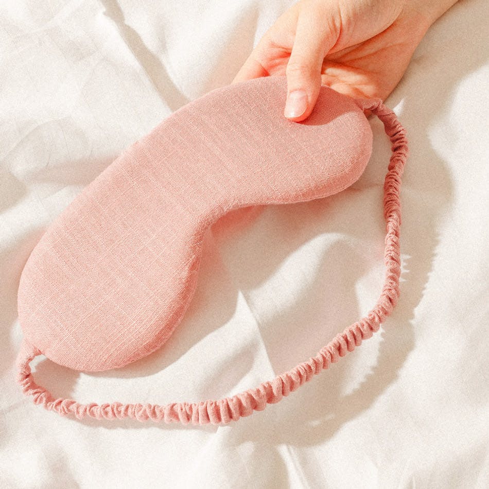Image of woman's hand holding sleep mask