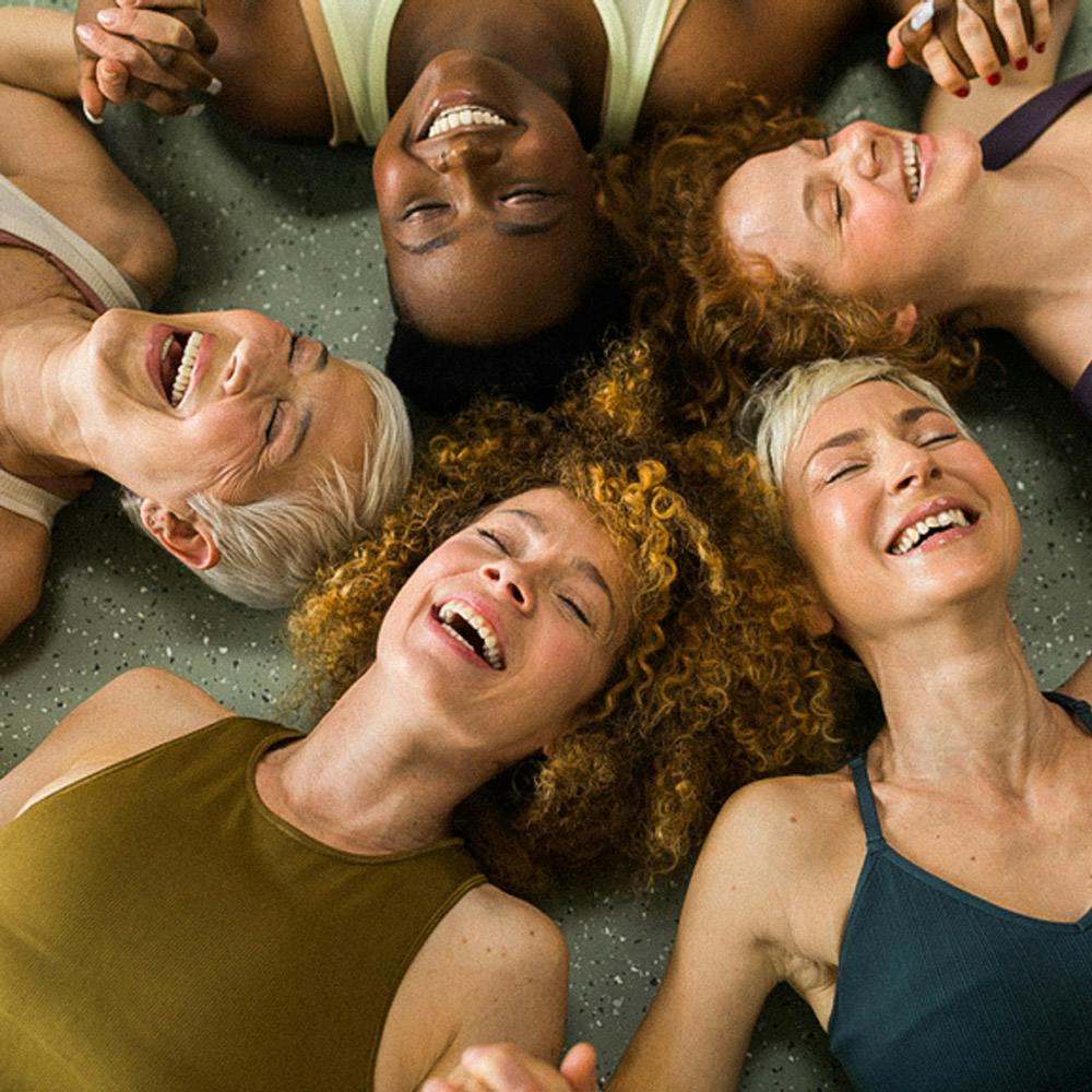 Diverse group of women In workout clothing lying close together on the floor