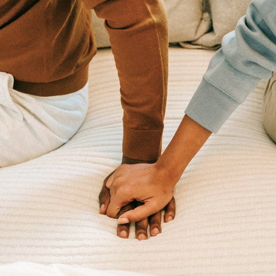 A couple holding hands on a bed together