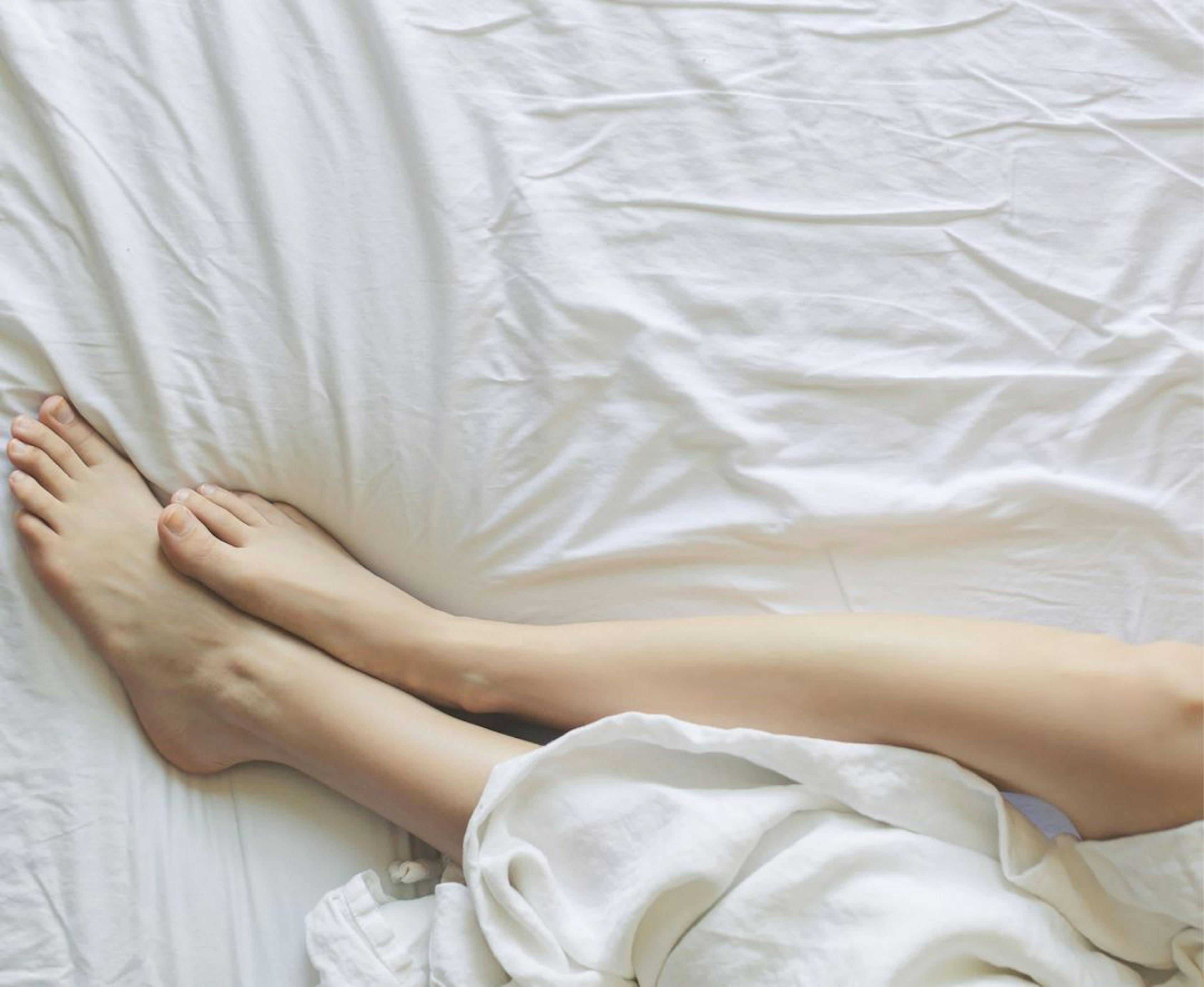 woman's legs wrapped up in bed sheets on bed