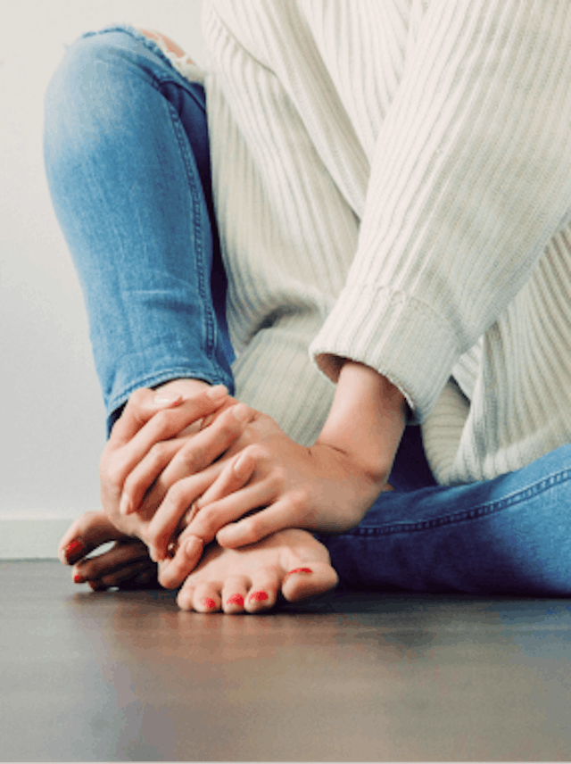 Woman sitting with hands on feet