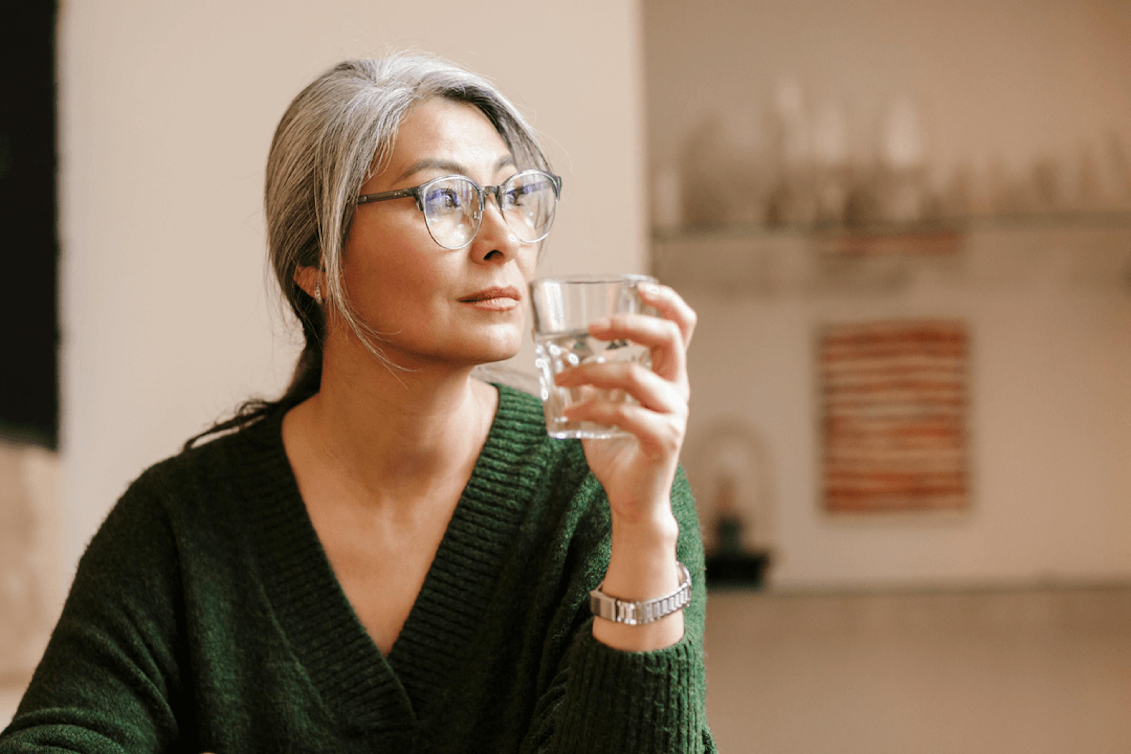 Woman sipping water looking anxiously into the distance