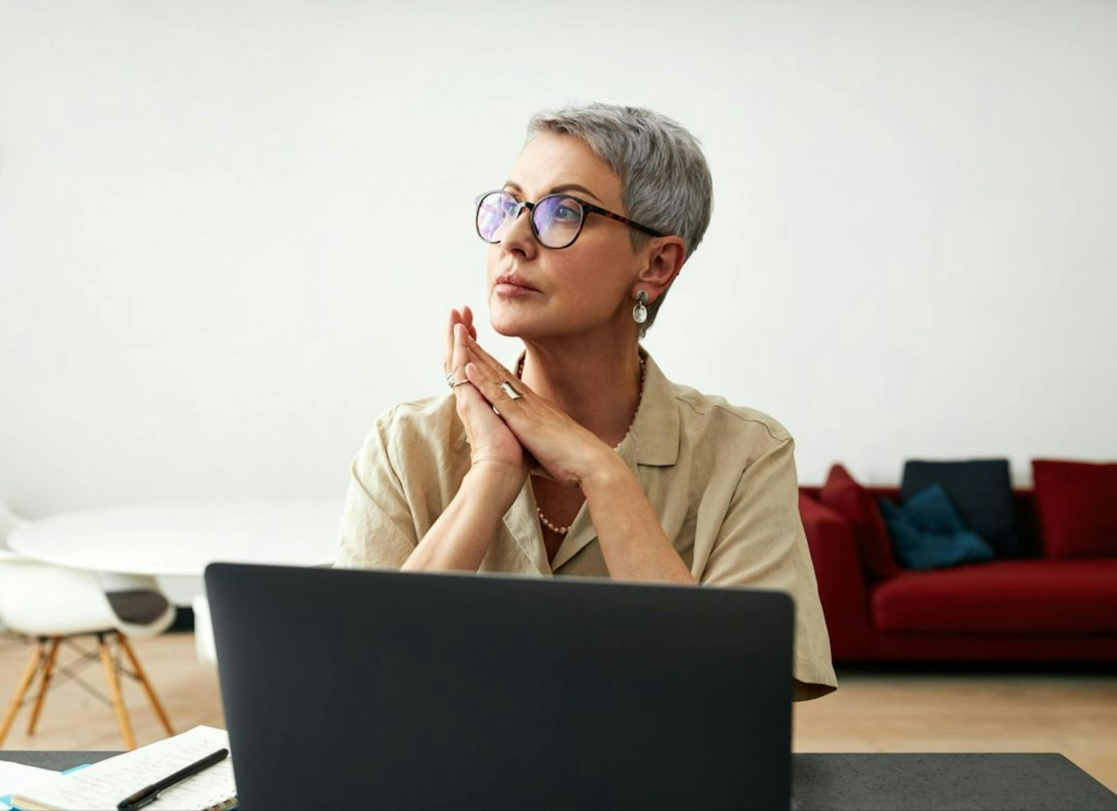 Woman looking Into distance while sitting at her laptop