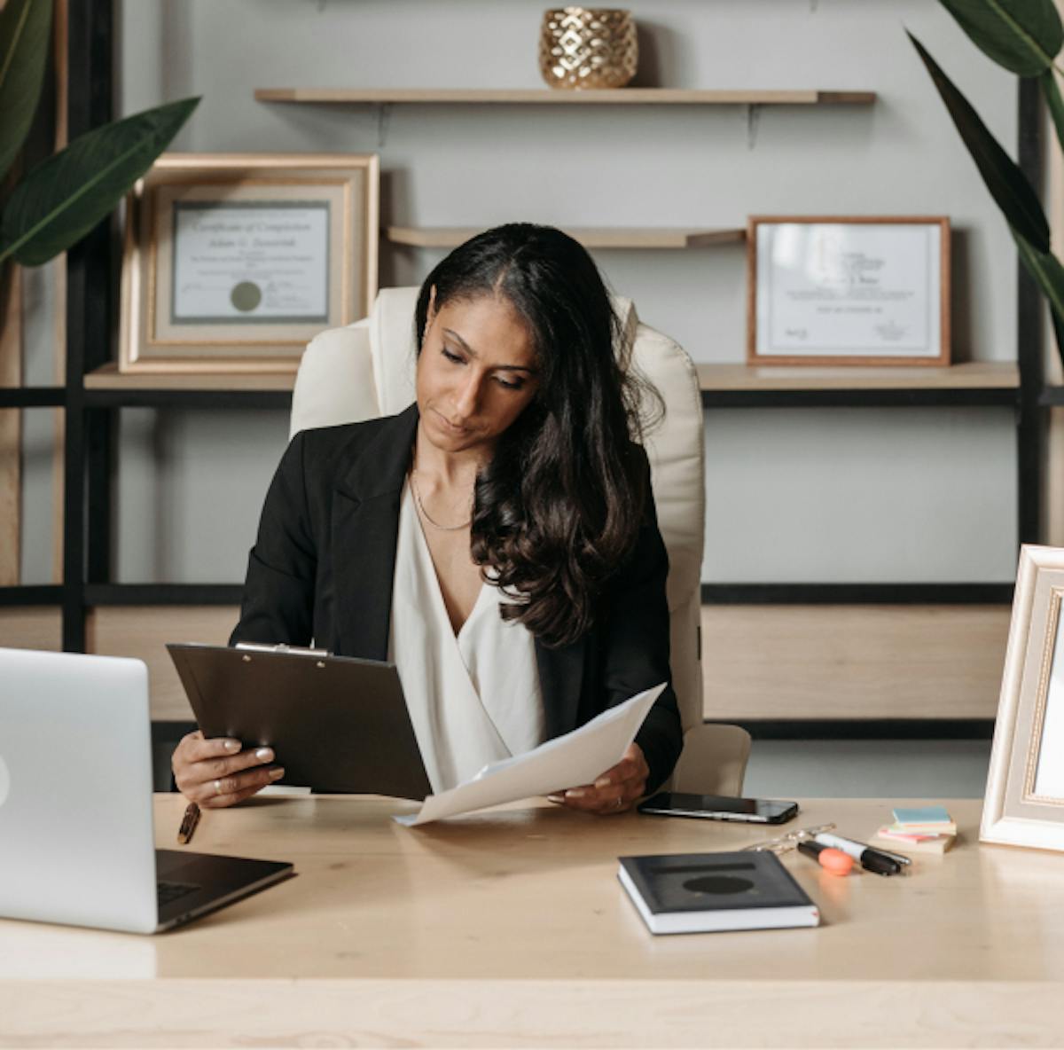 Woman at a desk looking at her clipboard and papers