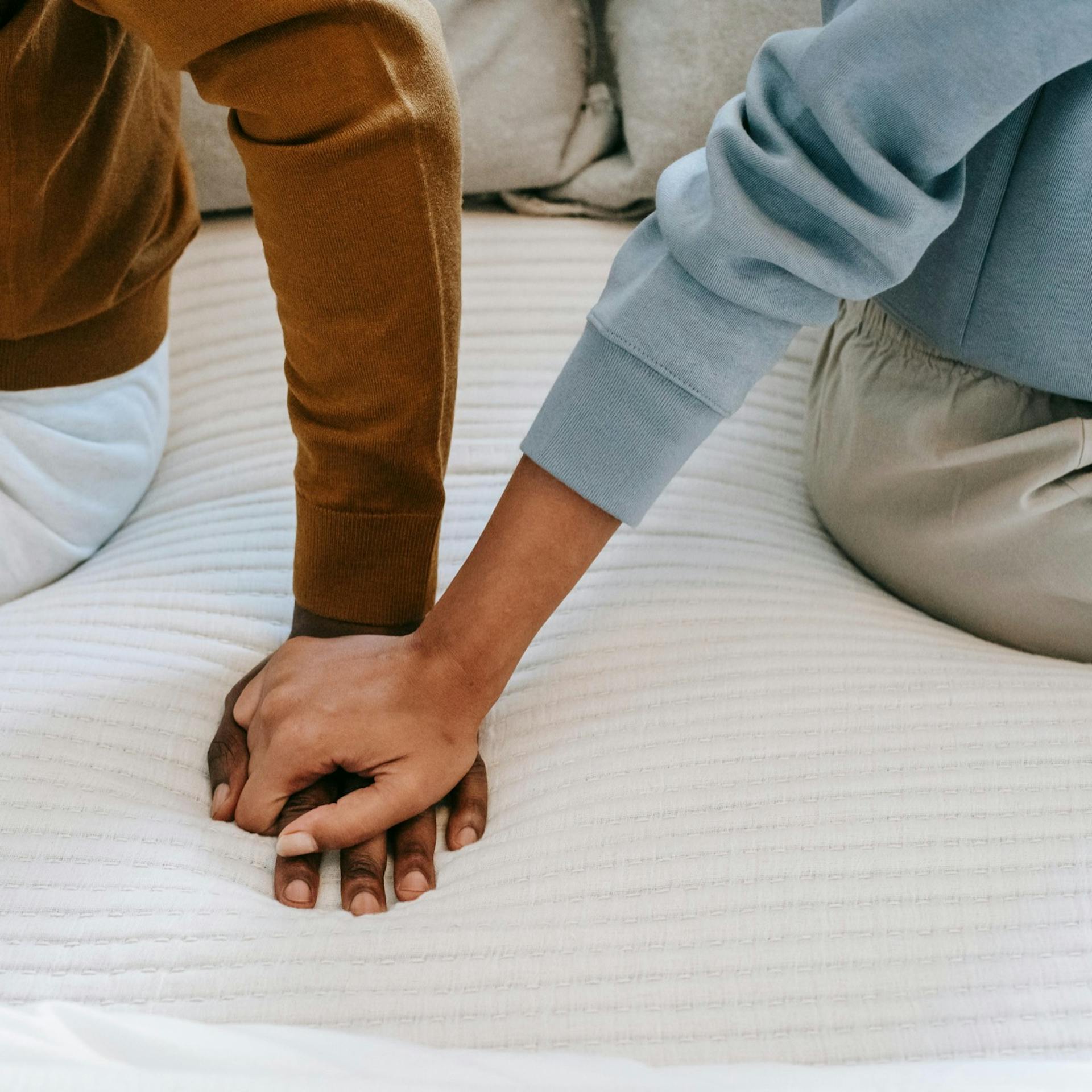 A couple holding hands on a bed together