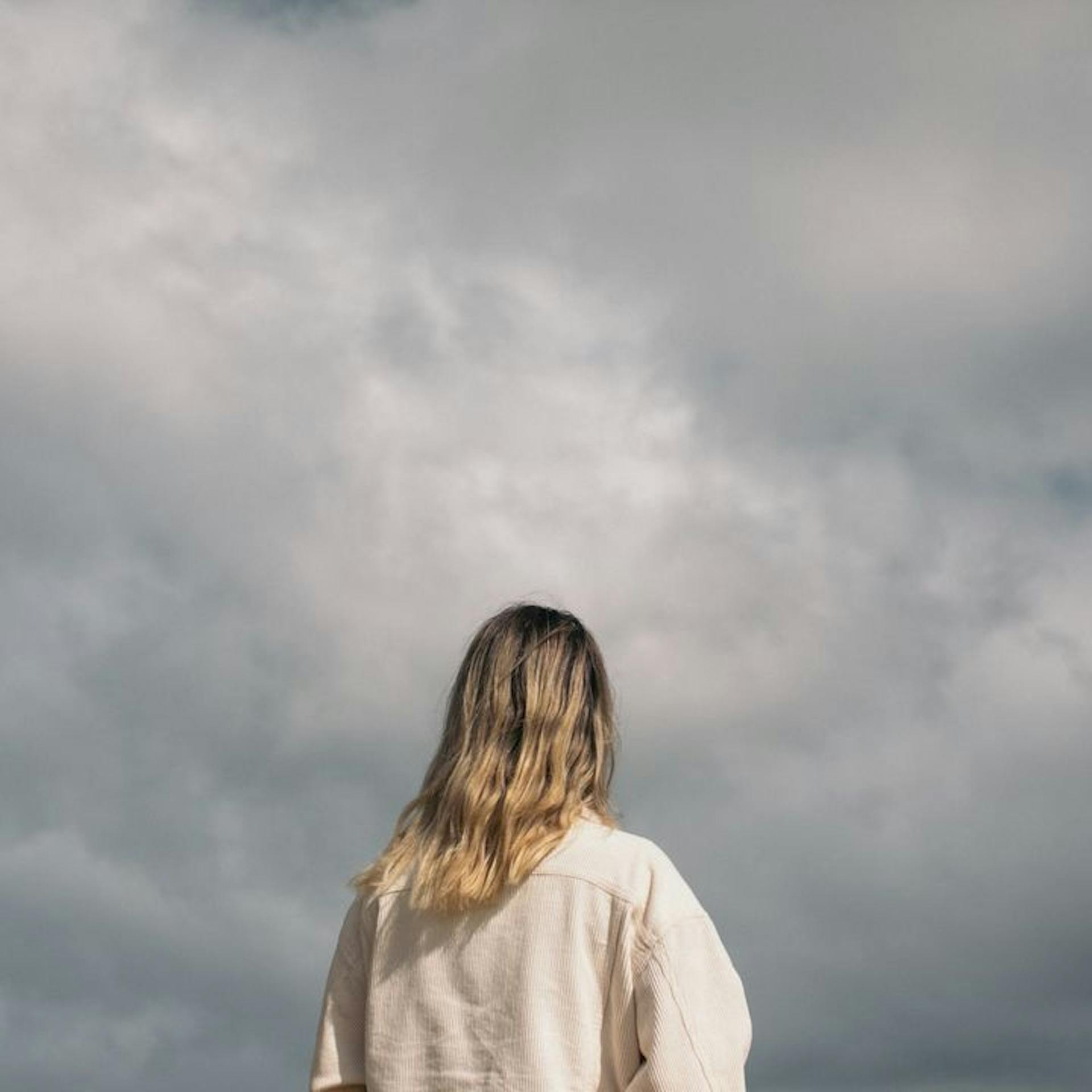 Back of a woman's head looking at dark stormclouds in the distance