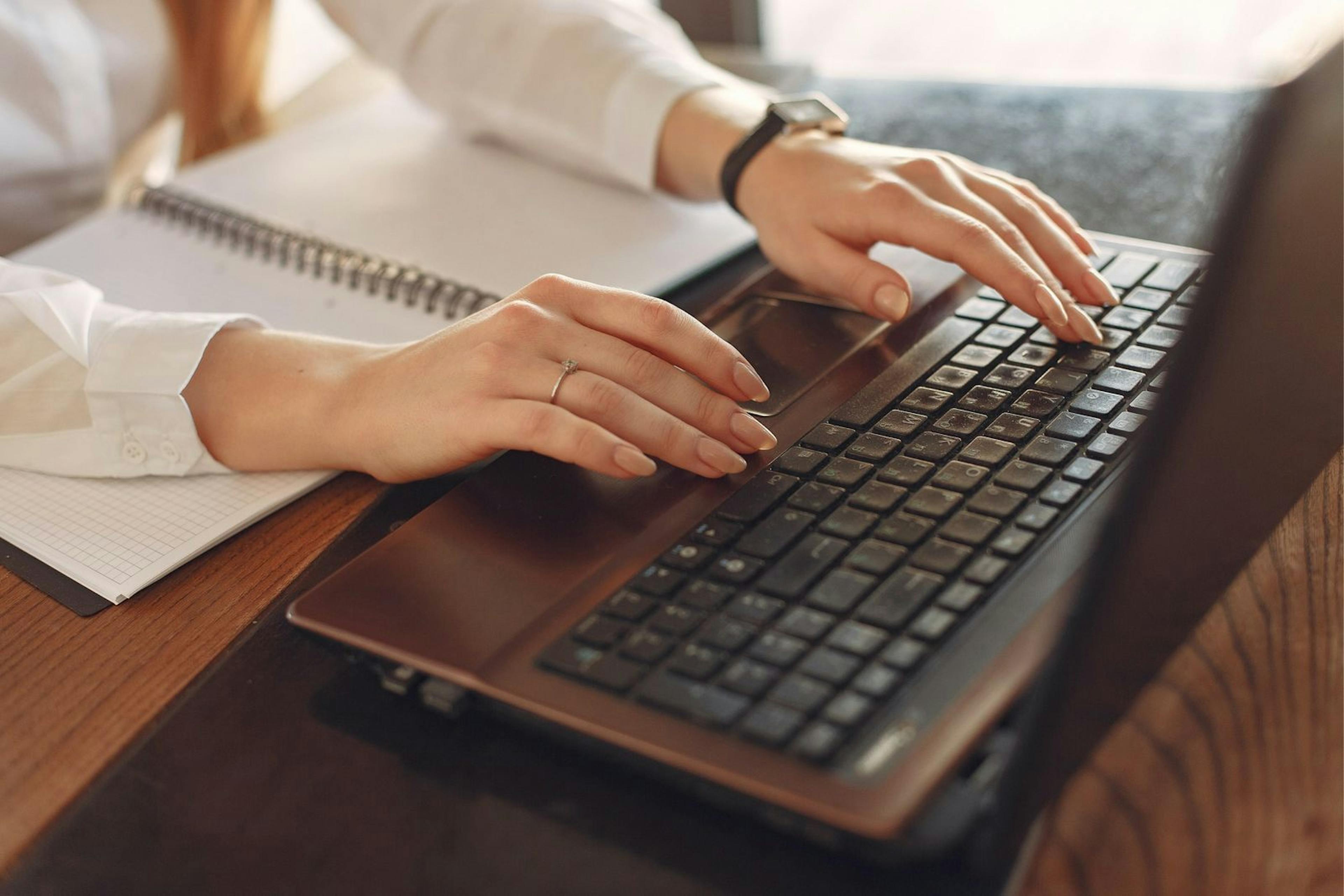 Image of a woman's hands typing on a computer