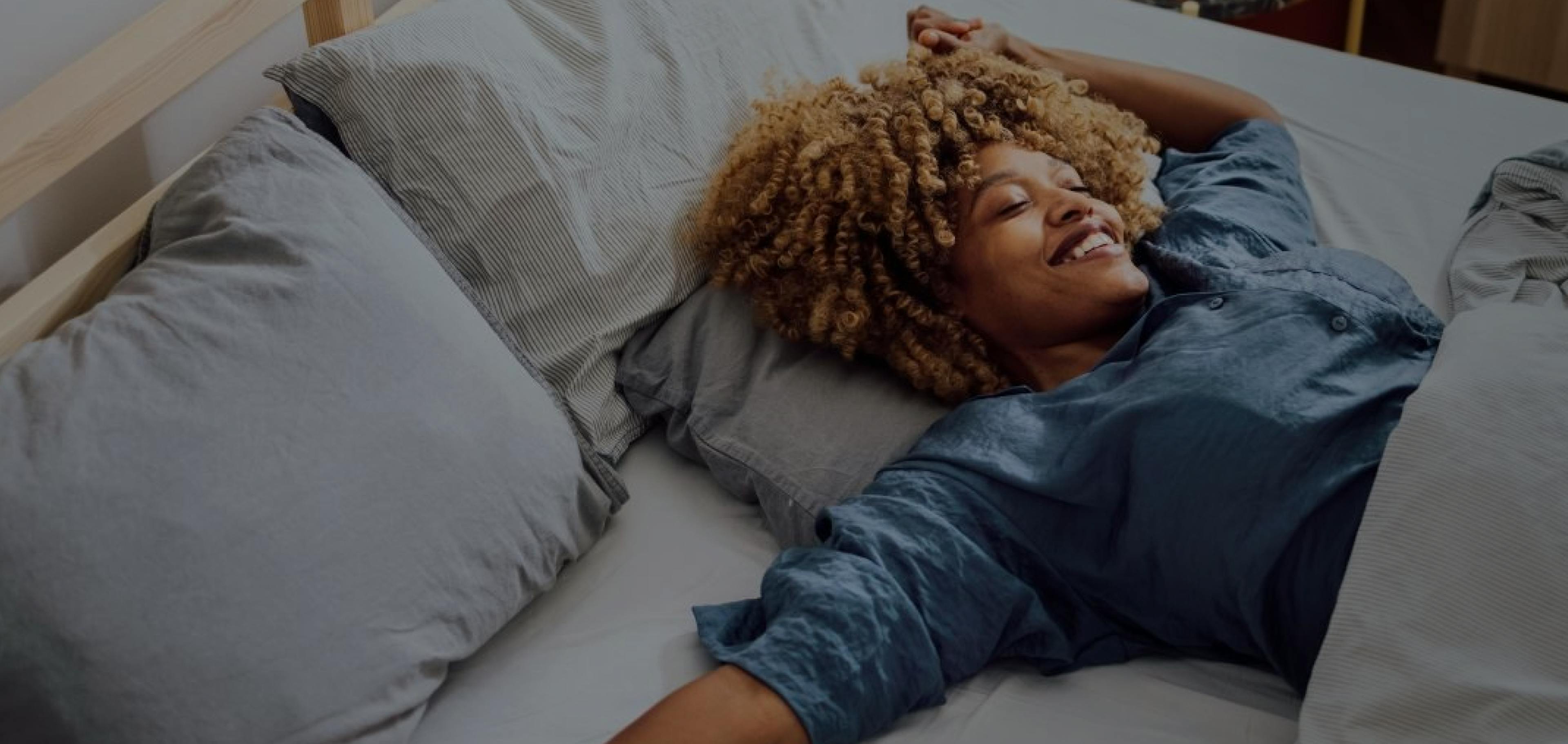 Woman laying on her bed looking up smiling