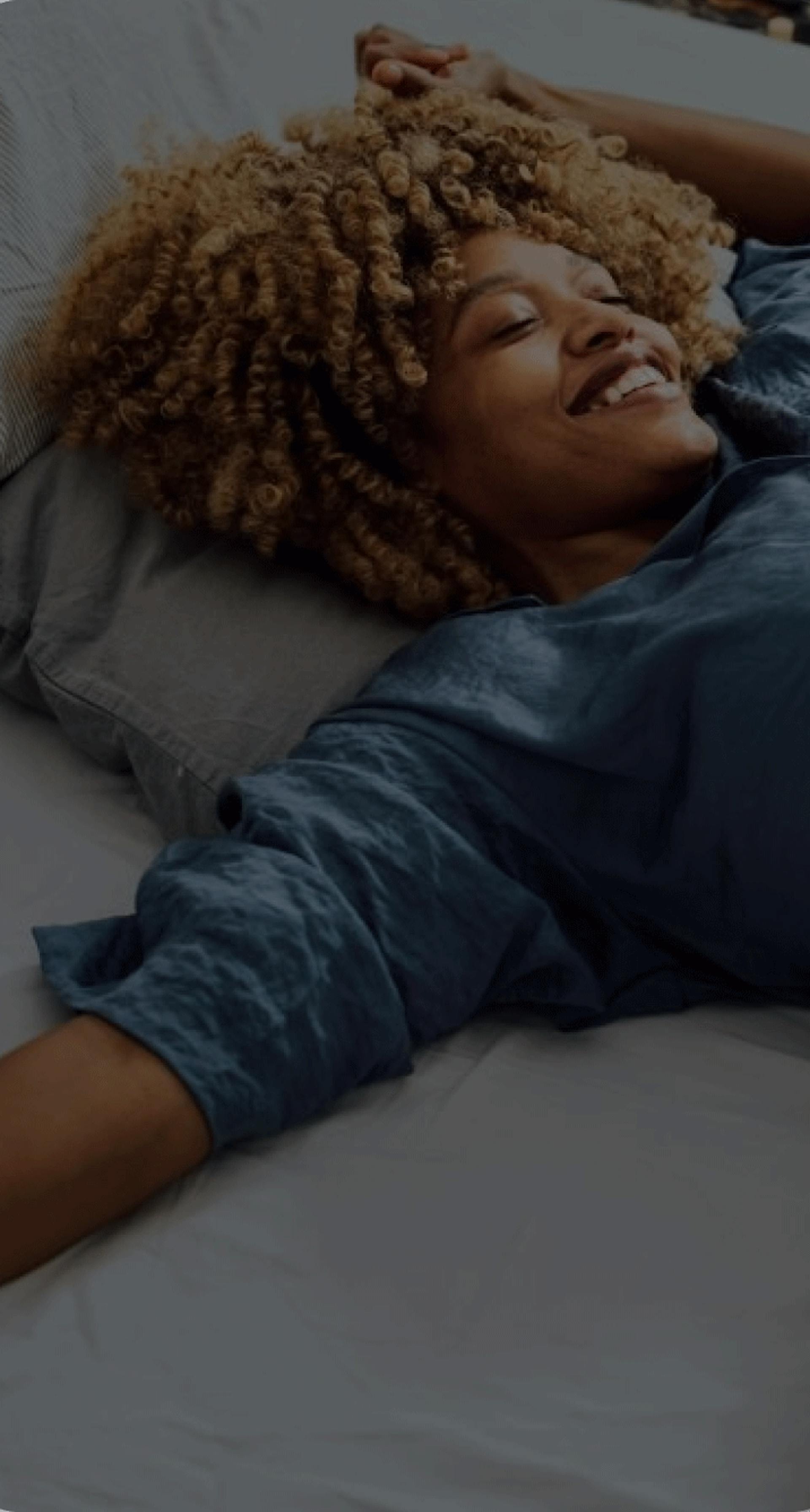 Woman laying on her bed looking up smiling