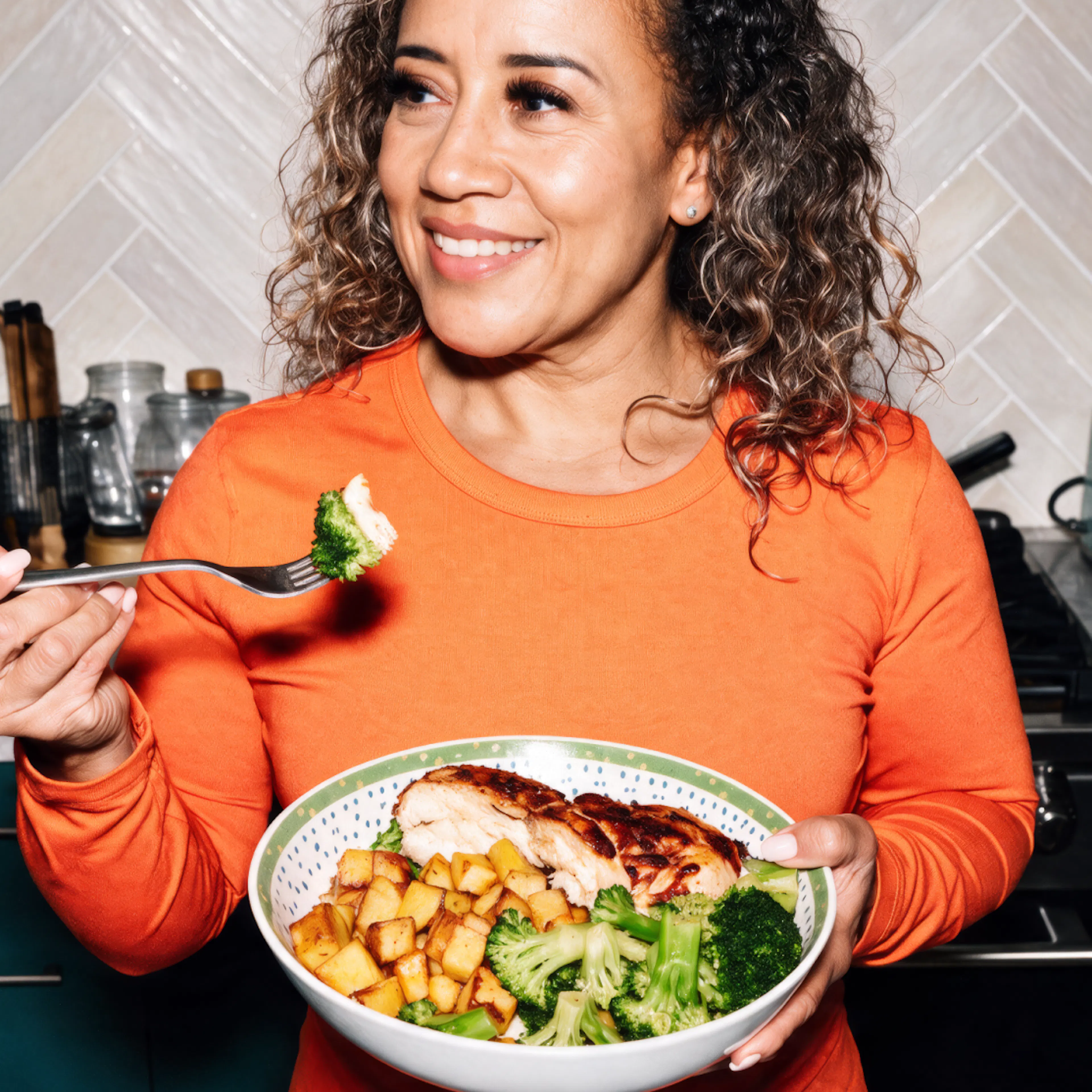 A woman in menopause eating a protein-forward meal with chicken and broccoli.