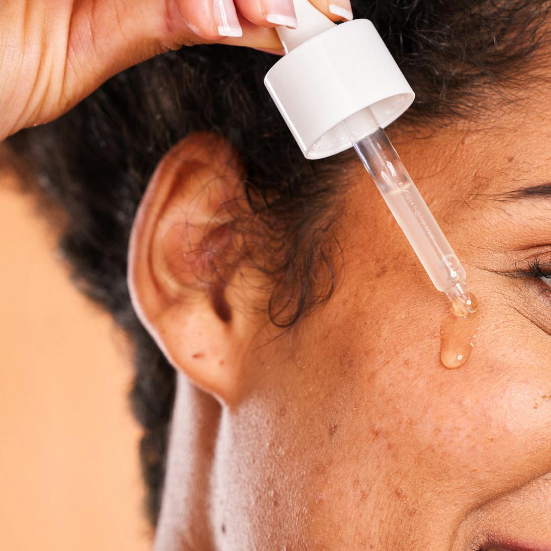 woman dropping oil skincare product on face