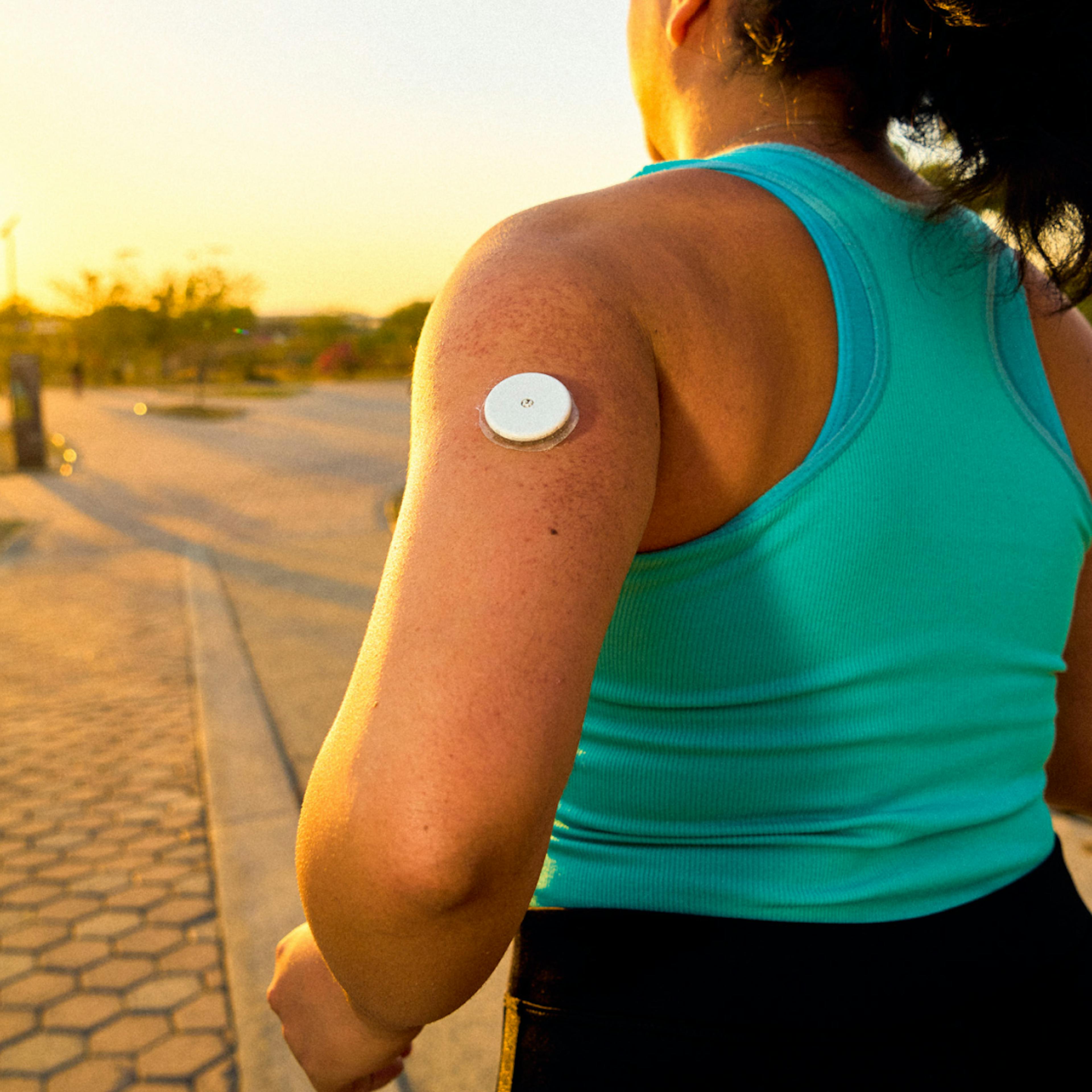 woman running with a CGM on her arm