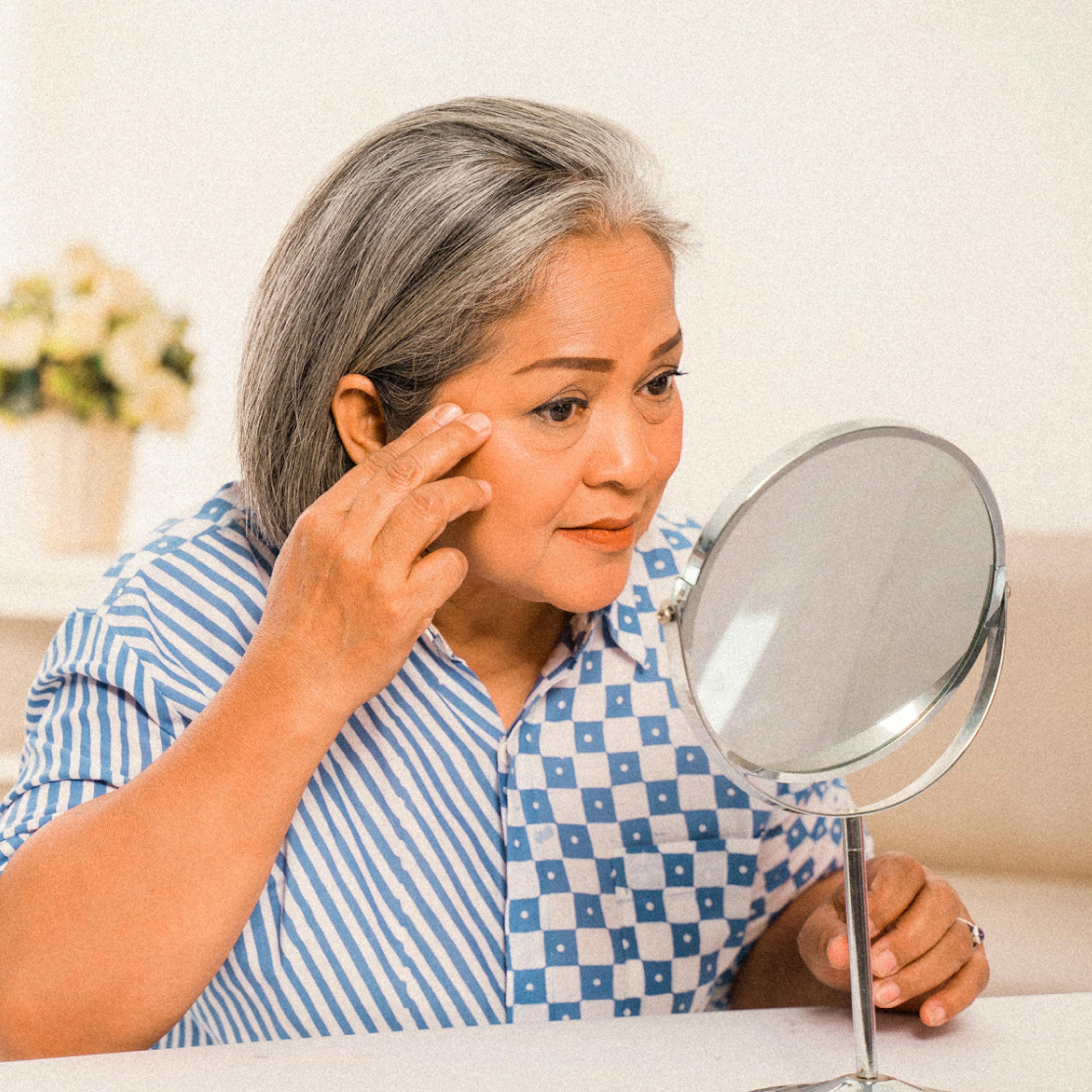 woman looking at her skin the mirror