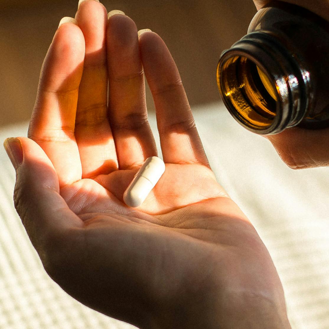 woman pouring a probiotic pill into her hand