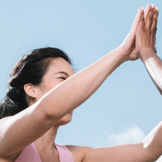 Photograph of woman smiling whilst high-fiving another woman