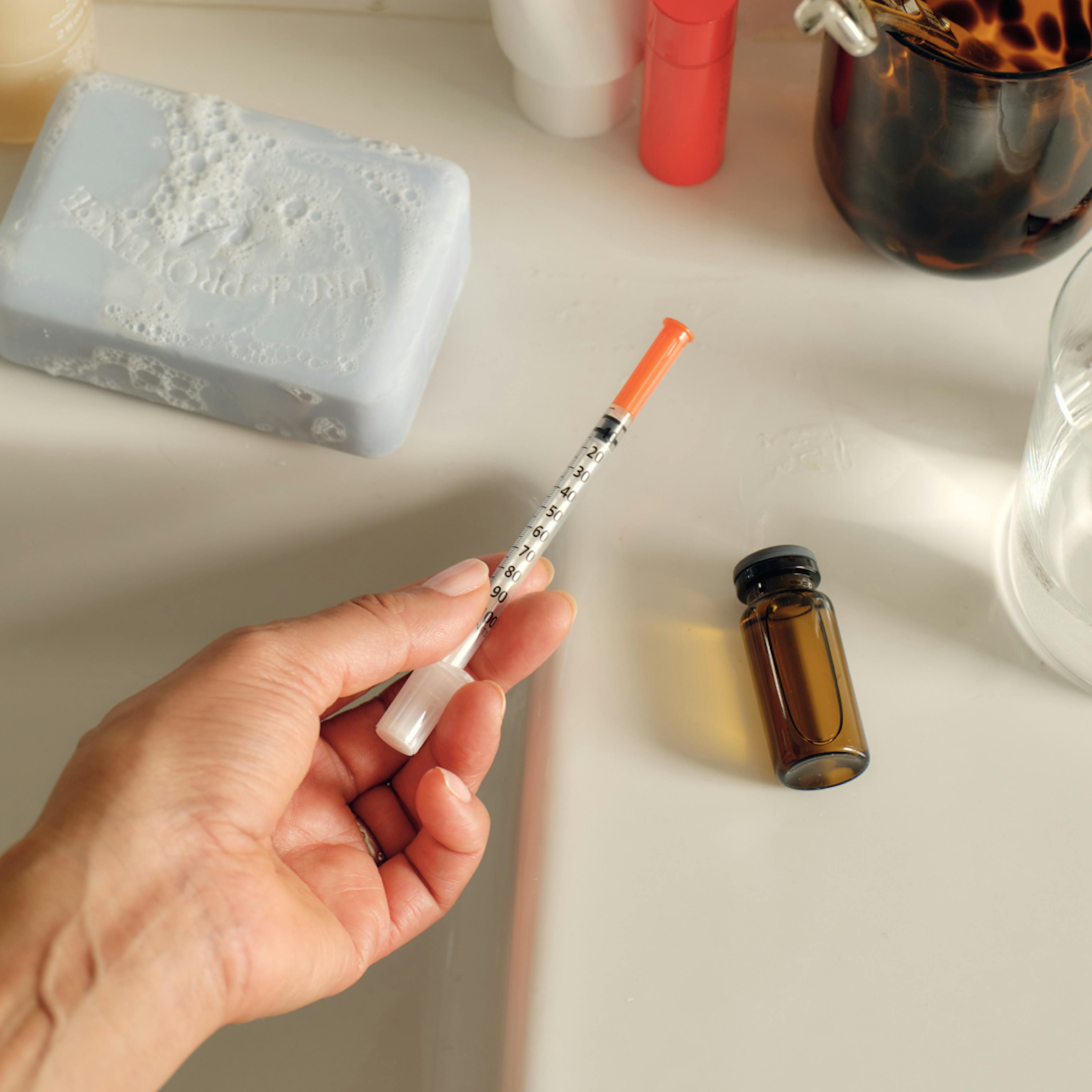 Woman holding injectable GLP-1 for demonstrative purposes