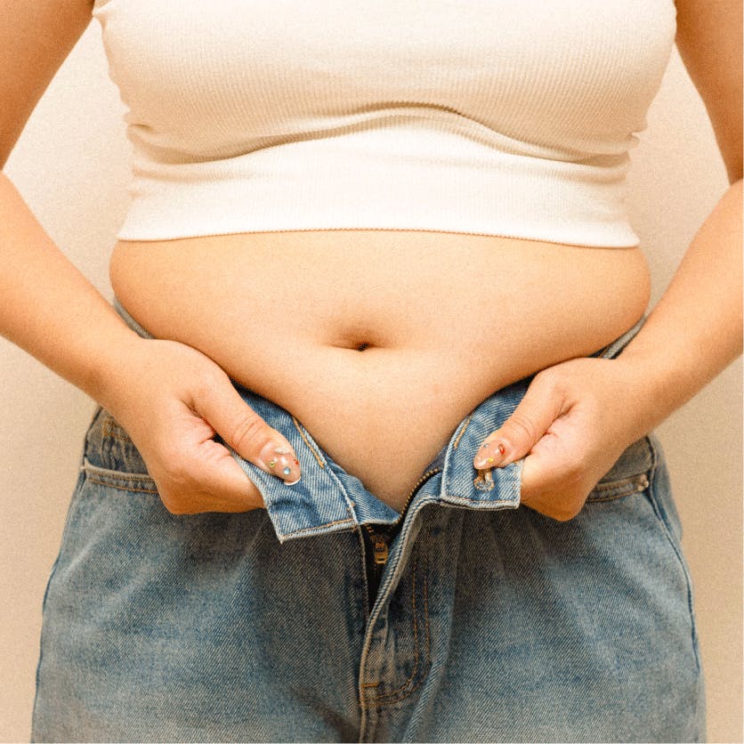 woman trying to button pants around her cortisol belly