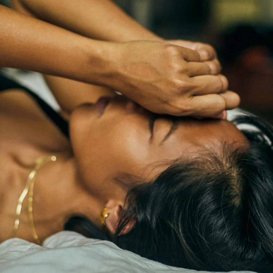 woman lying down with hands on face