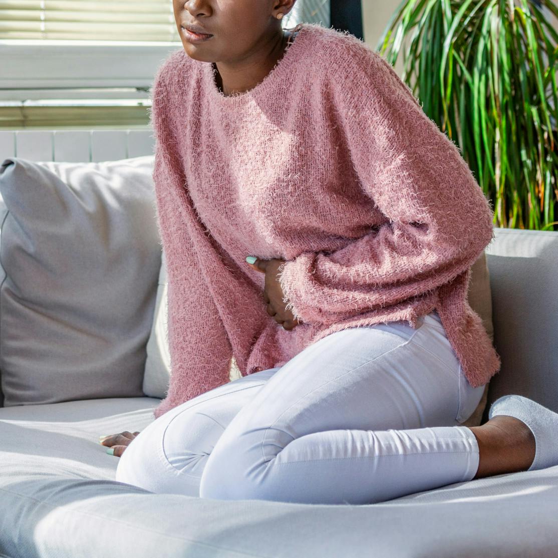 woman in perimenopause sitting on couch holding her stomach