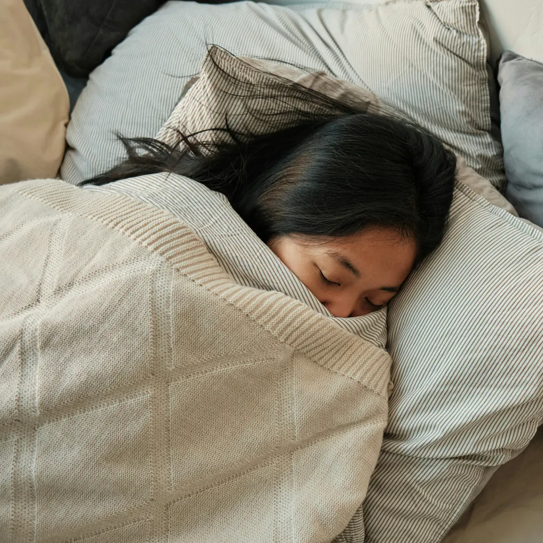 A woman peacefully sleeping with the covers up high.