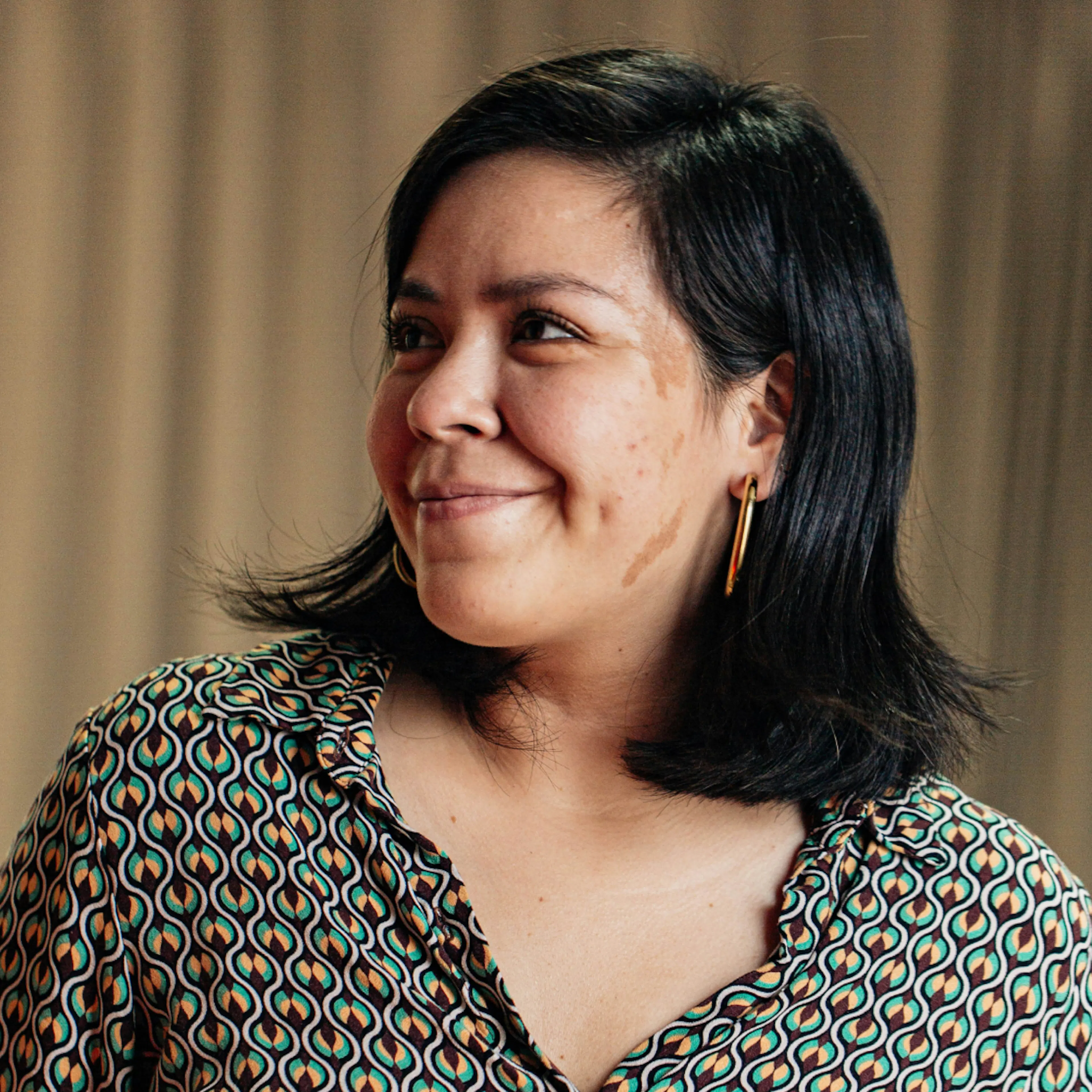 A woman in midlife smiling and looking to the side. She's contemplating taking an omega-3 supplement for women.