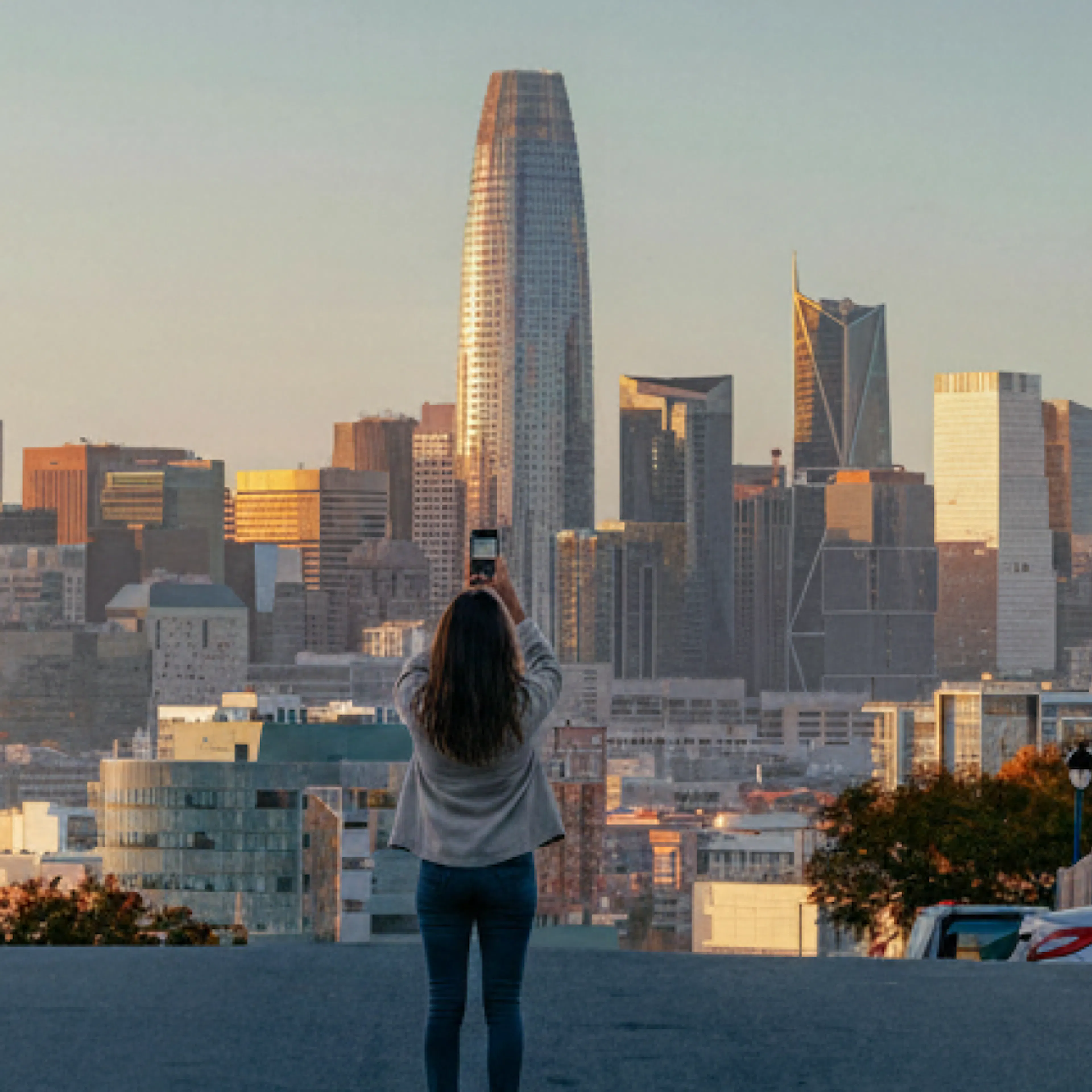 A woman taking a picture of the financial district in San Francisco.
