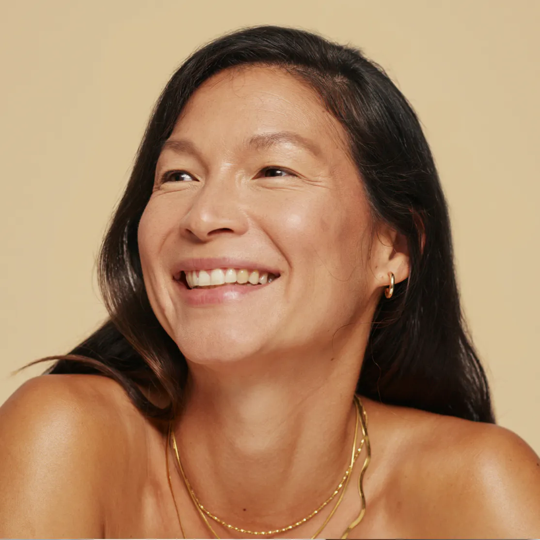 A woman in perimenopause smiling and looking away.