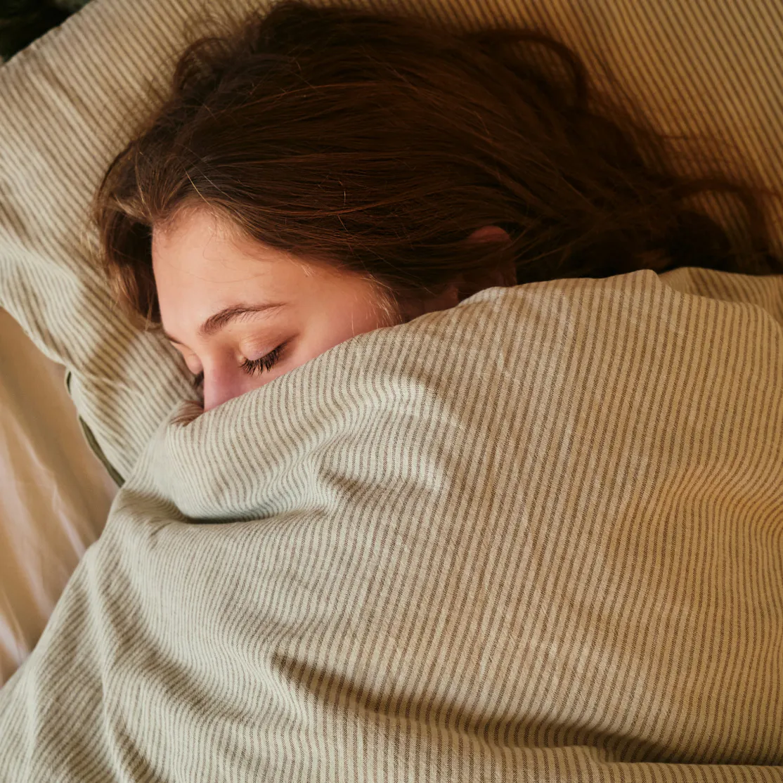 A woman in midlife sleeping soundly under the covers.