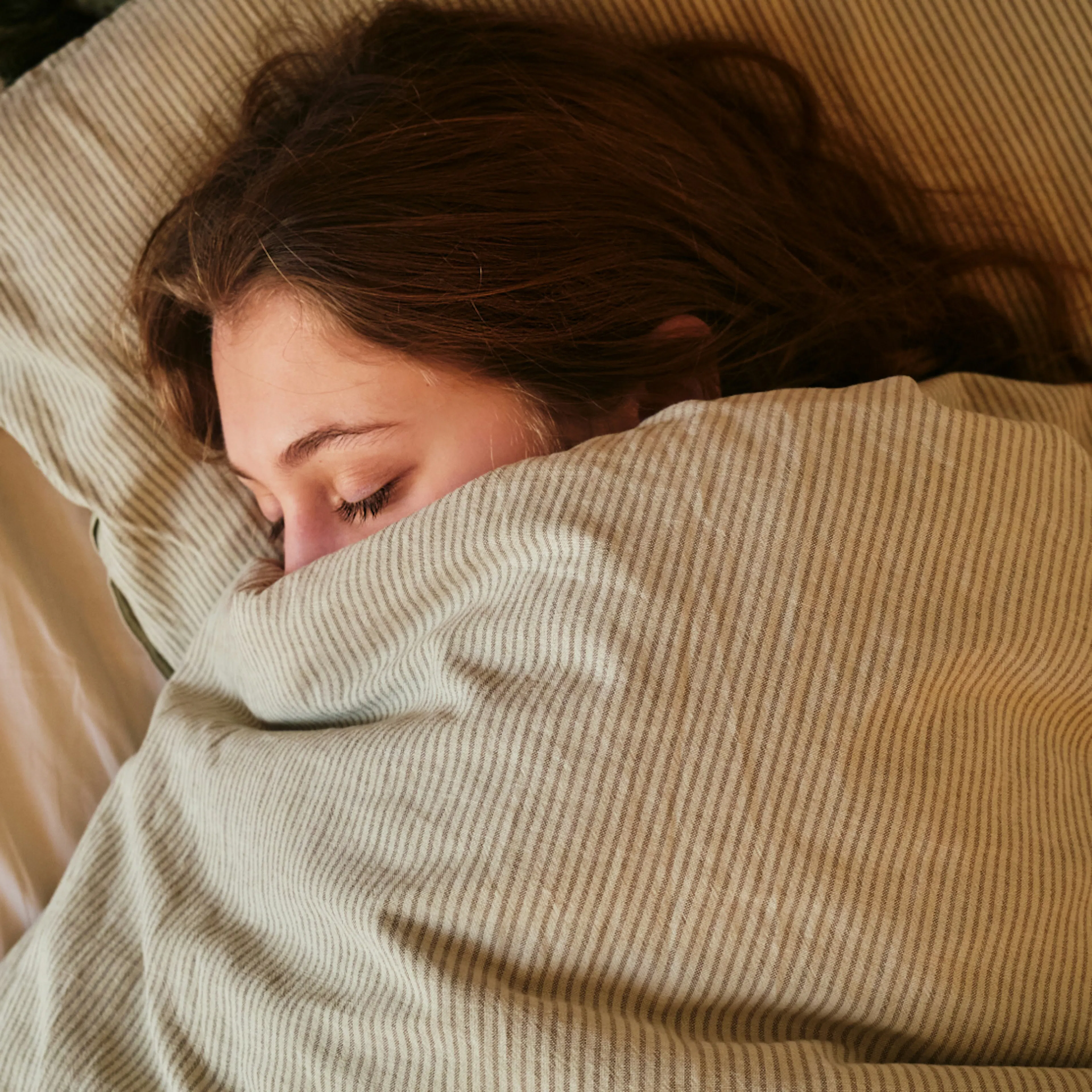 A woman in midlife sleeping soundly under the covers.