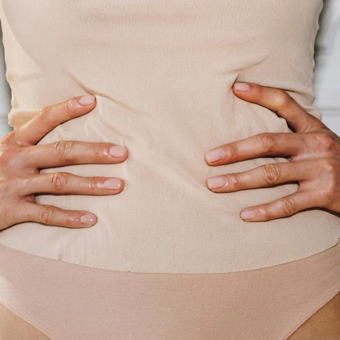 Close-up photo of a woman's hands on her waist. She's wondering if she has a yeast infection or a UTI.