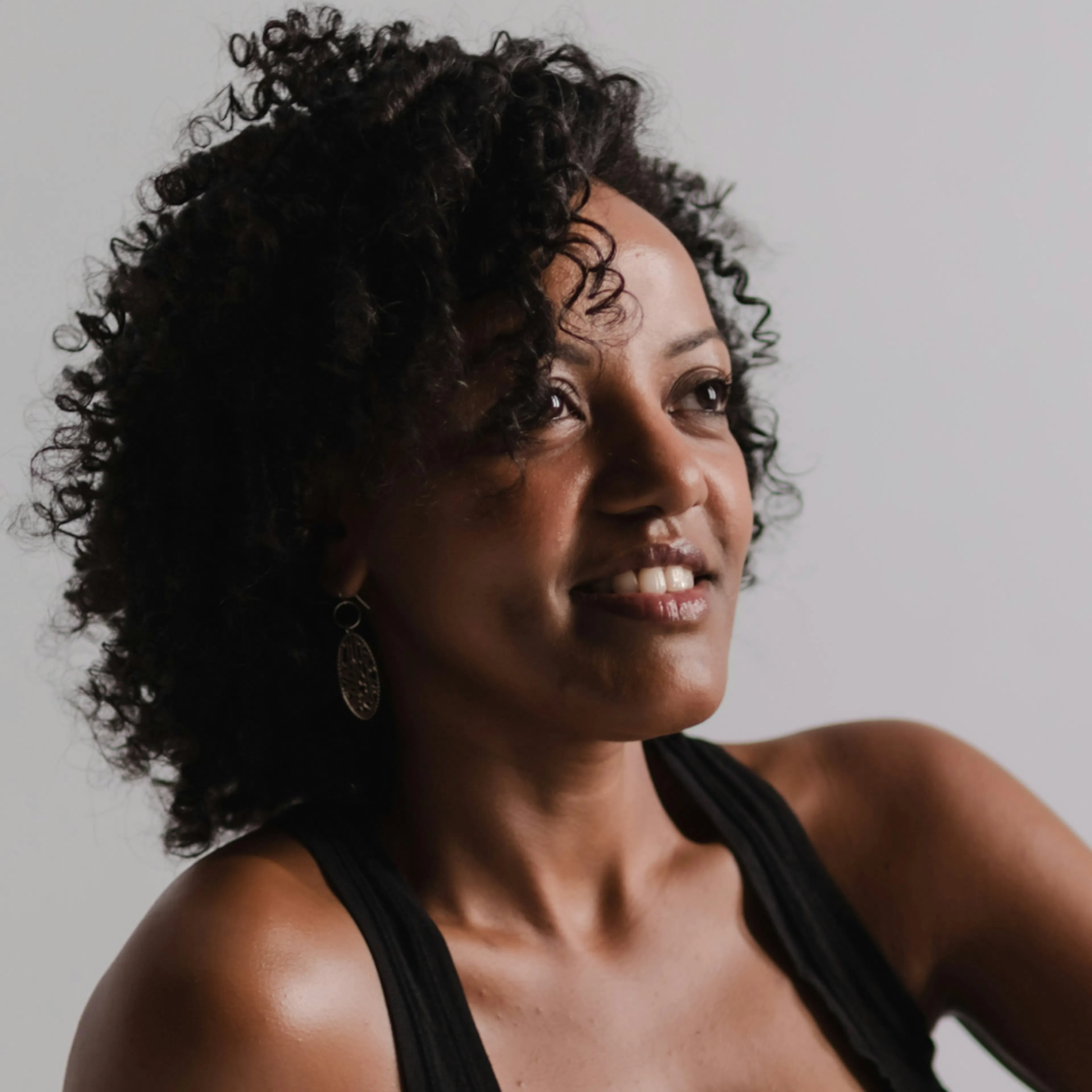 A woman in midlife smiling softly and looking off into the distance. 