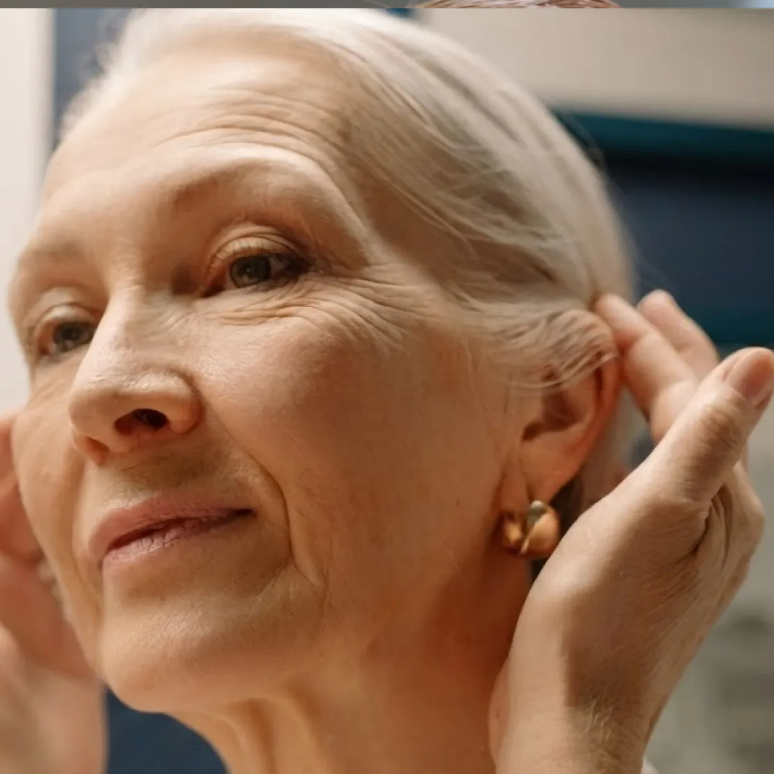 A close-up photo of a woman in midlife looking at her face.