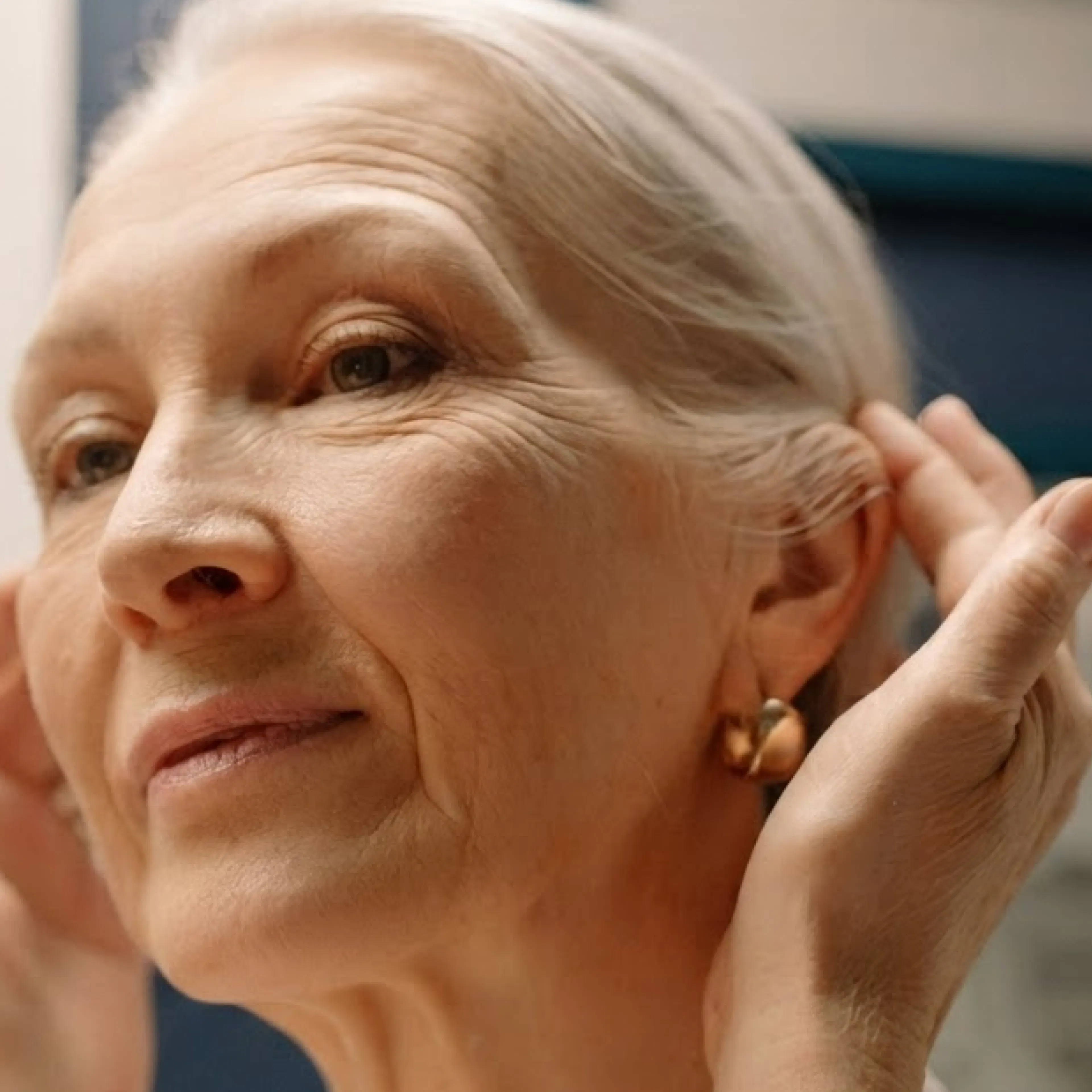 A close-up photo of a woman in midlife looking at her face.