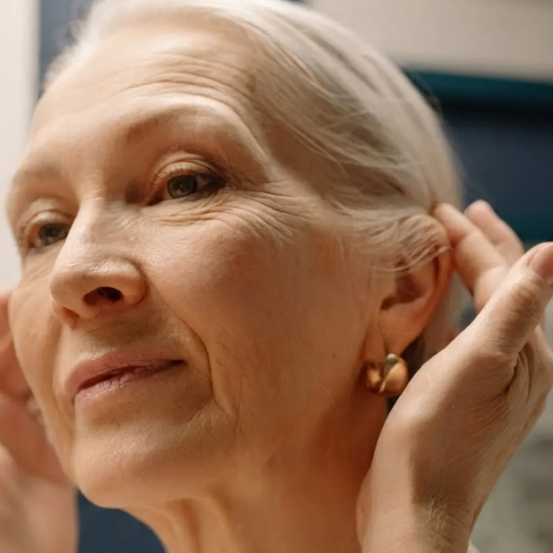 A close-up photo of a woman in midlife looking at her face.