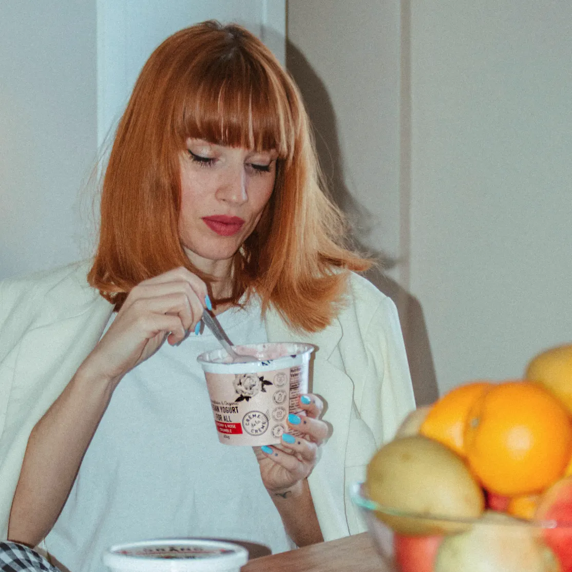A woman in midlife eating from a container of yogurt.