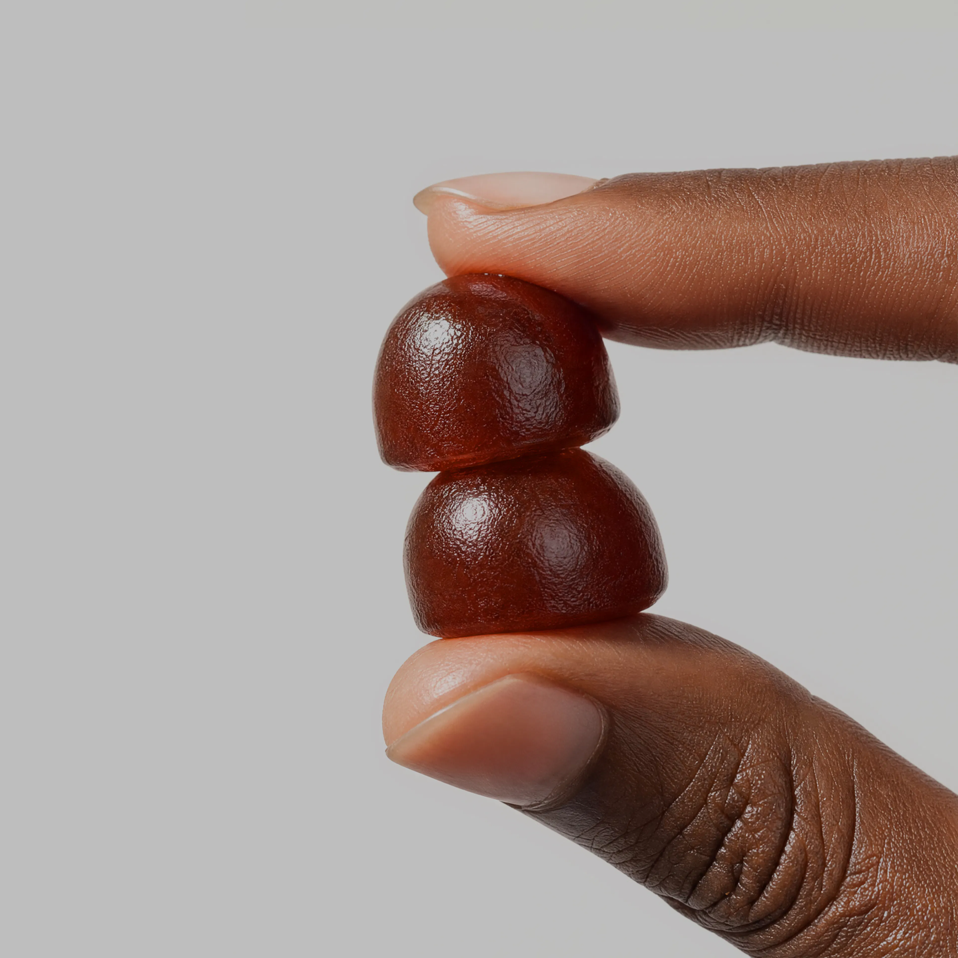 person holding two dark gummies in hand
