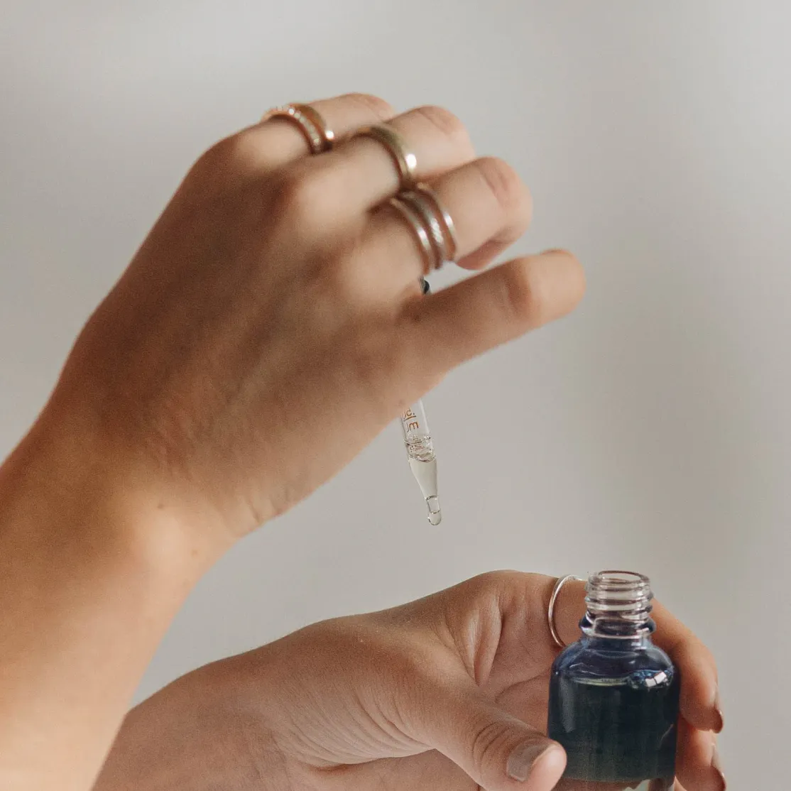 A close-up photo of a woman taking a dropper out a jar of essential oil for sleep.