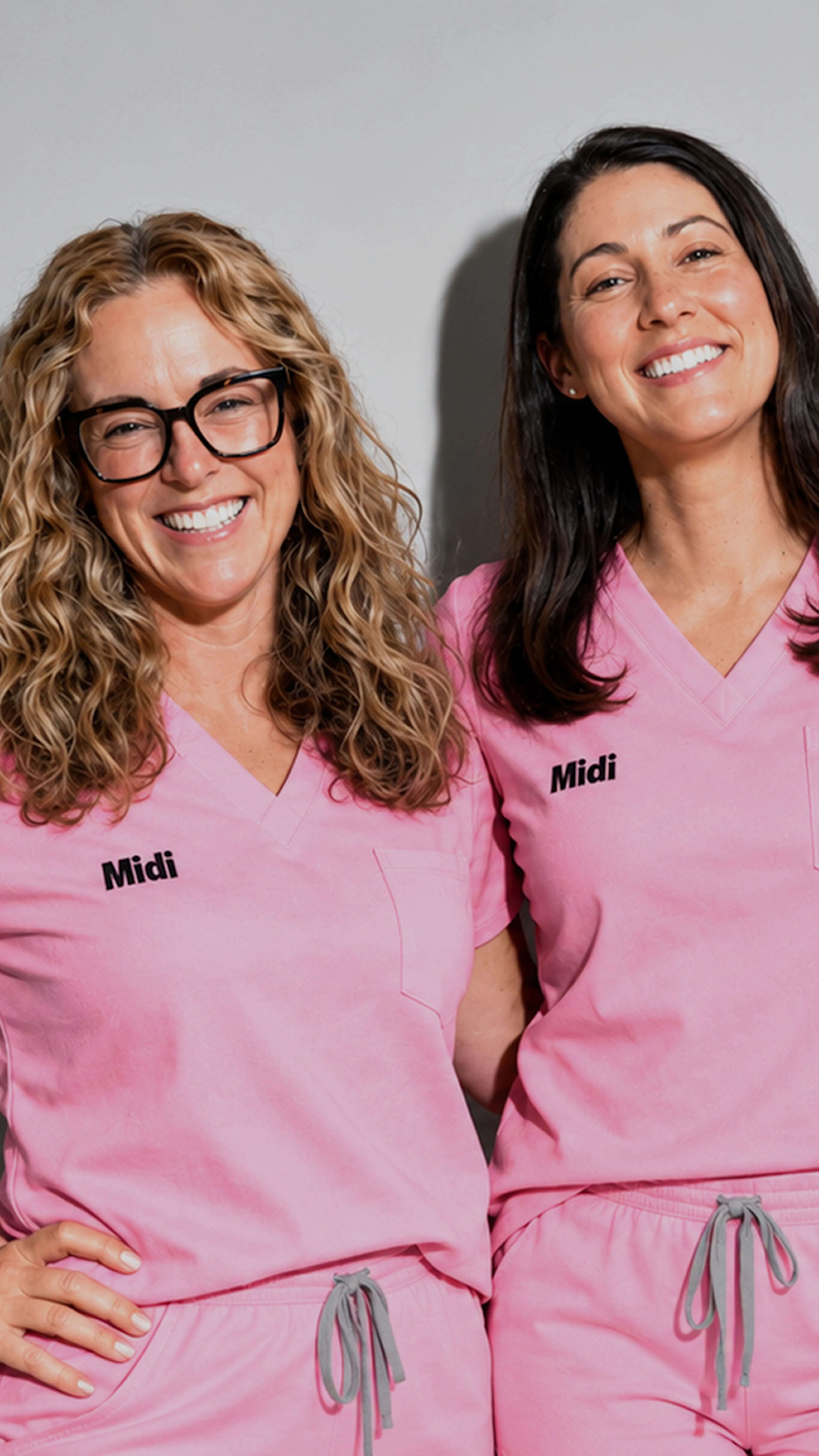 Two Midi clinicians smiling wearing pink scrubs