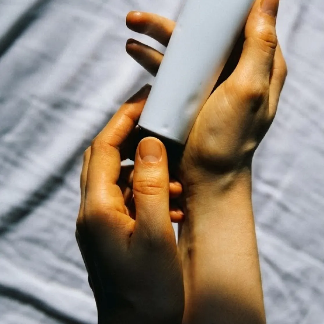A close-up photo of a woman holding a tube of metronidazole gel.