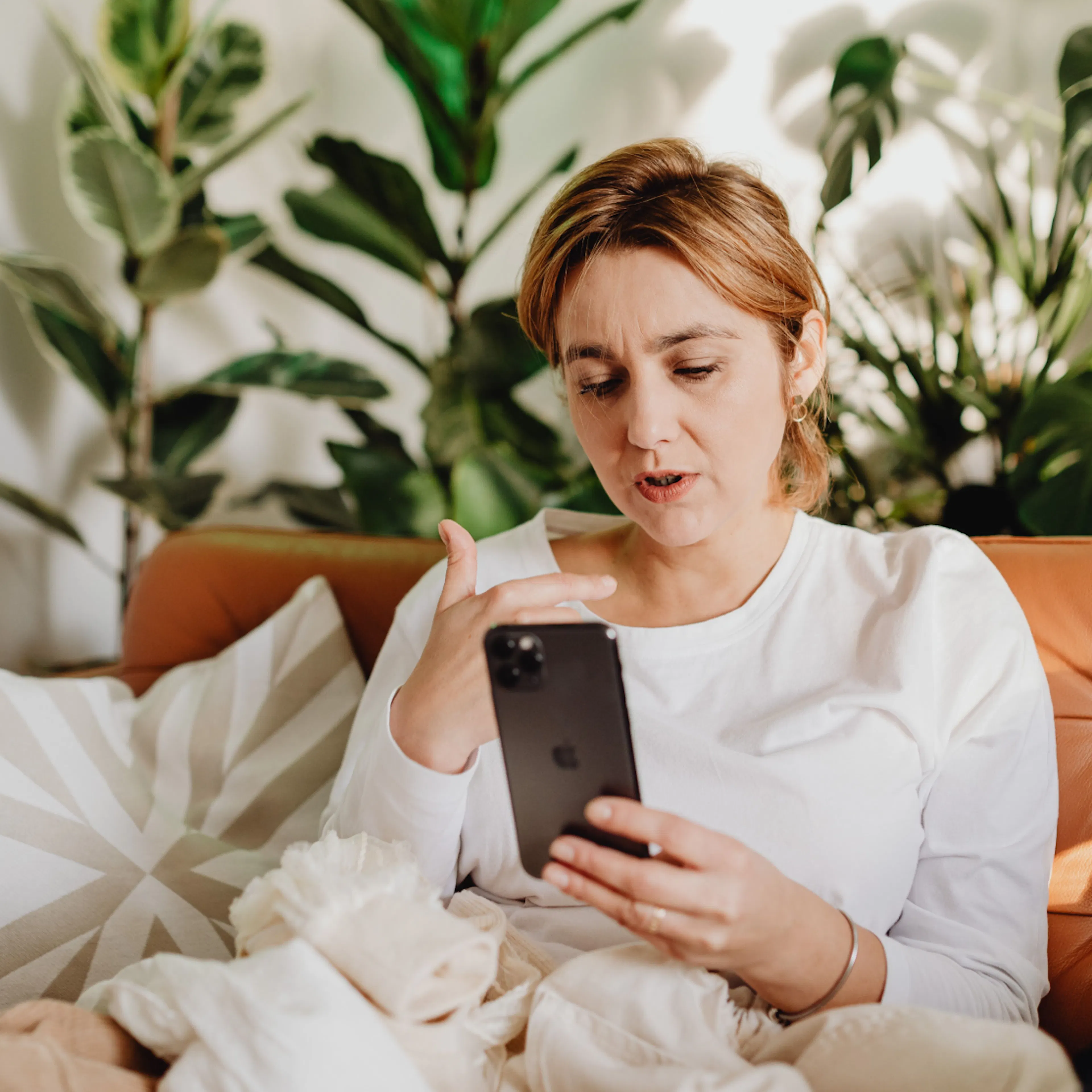 A woman in midlife, sitting at home and looking up progesterone side effects on her phone.