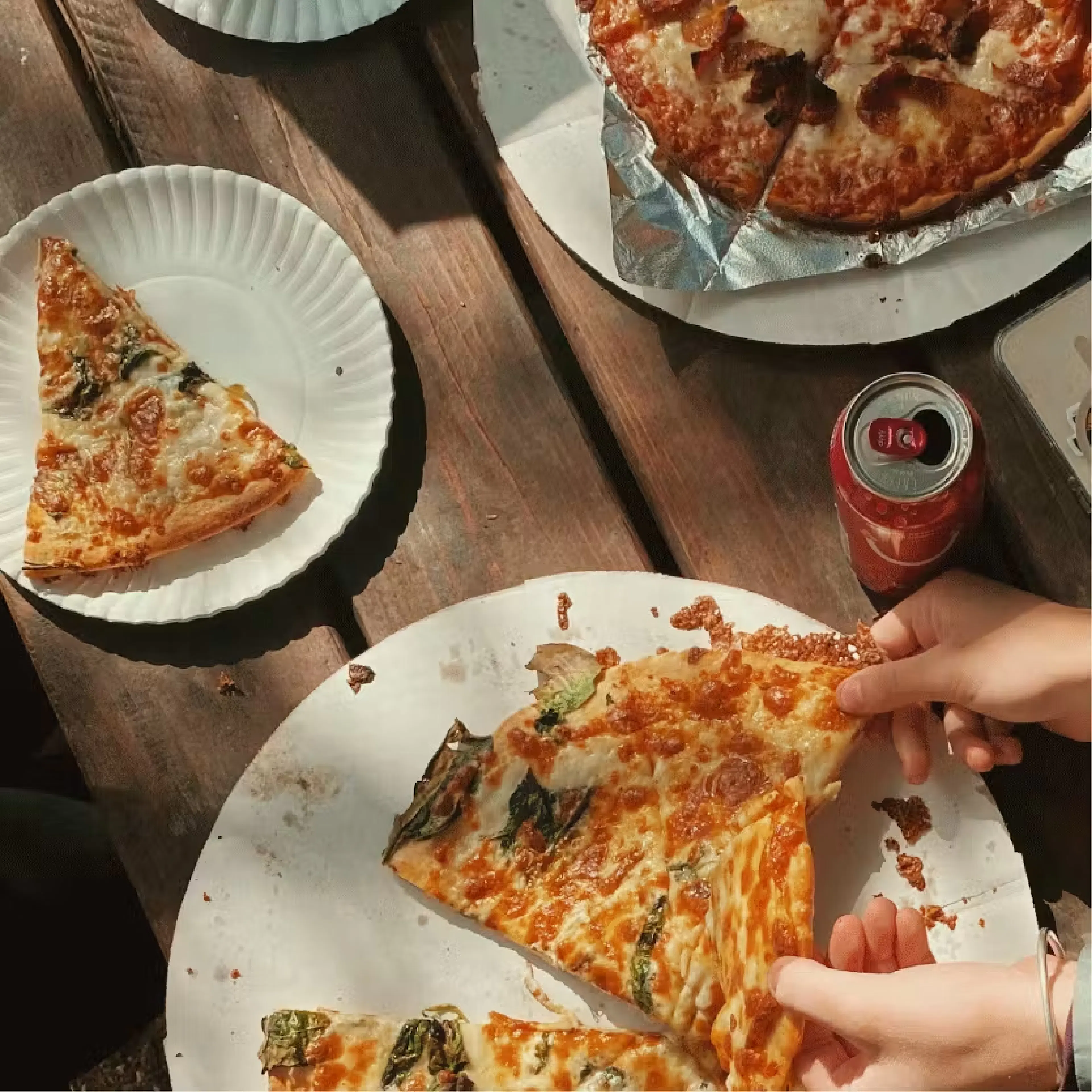 Hands grabbing pizza at wooden table