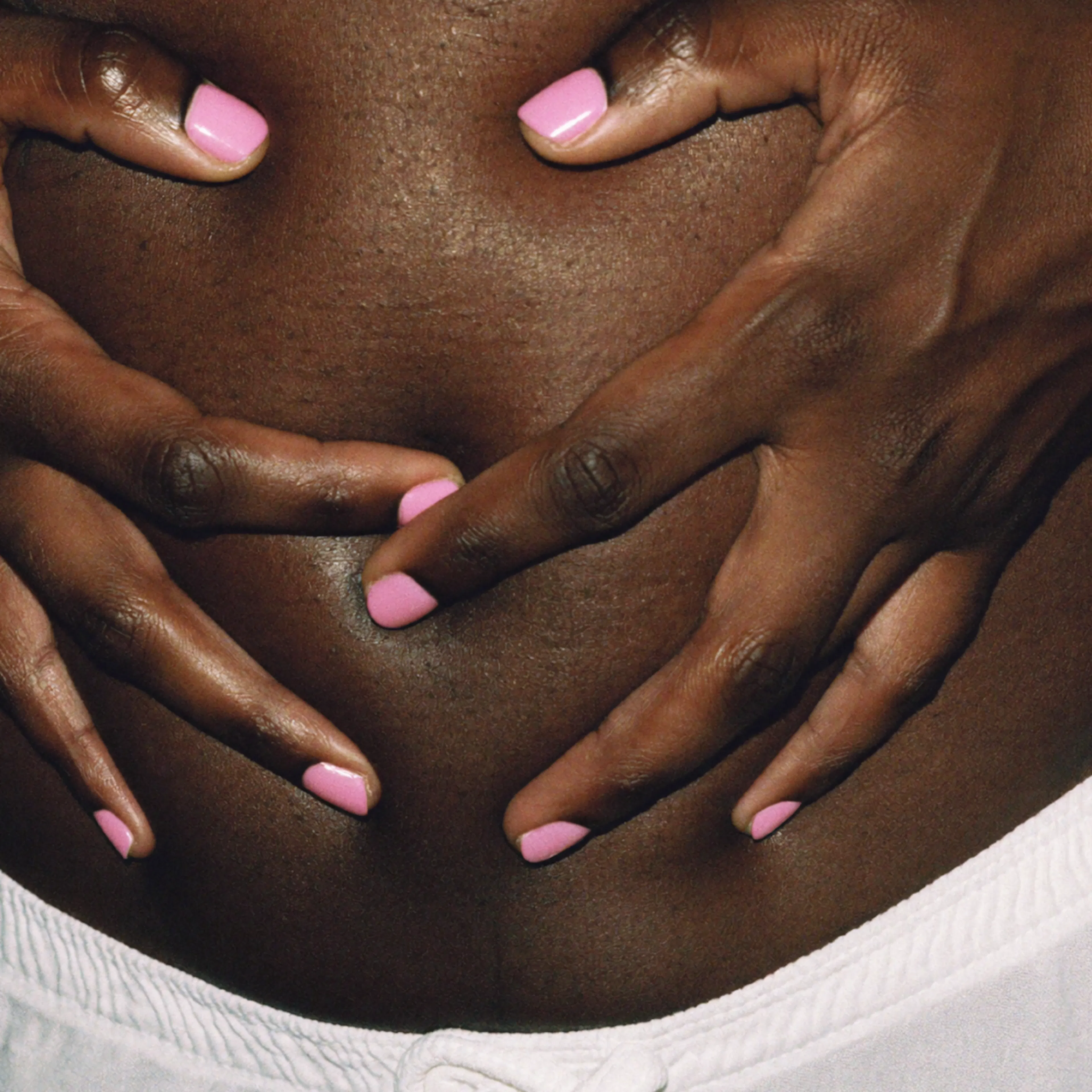 Close-up photo of a woman's hands on her belly.