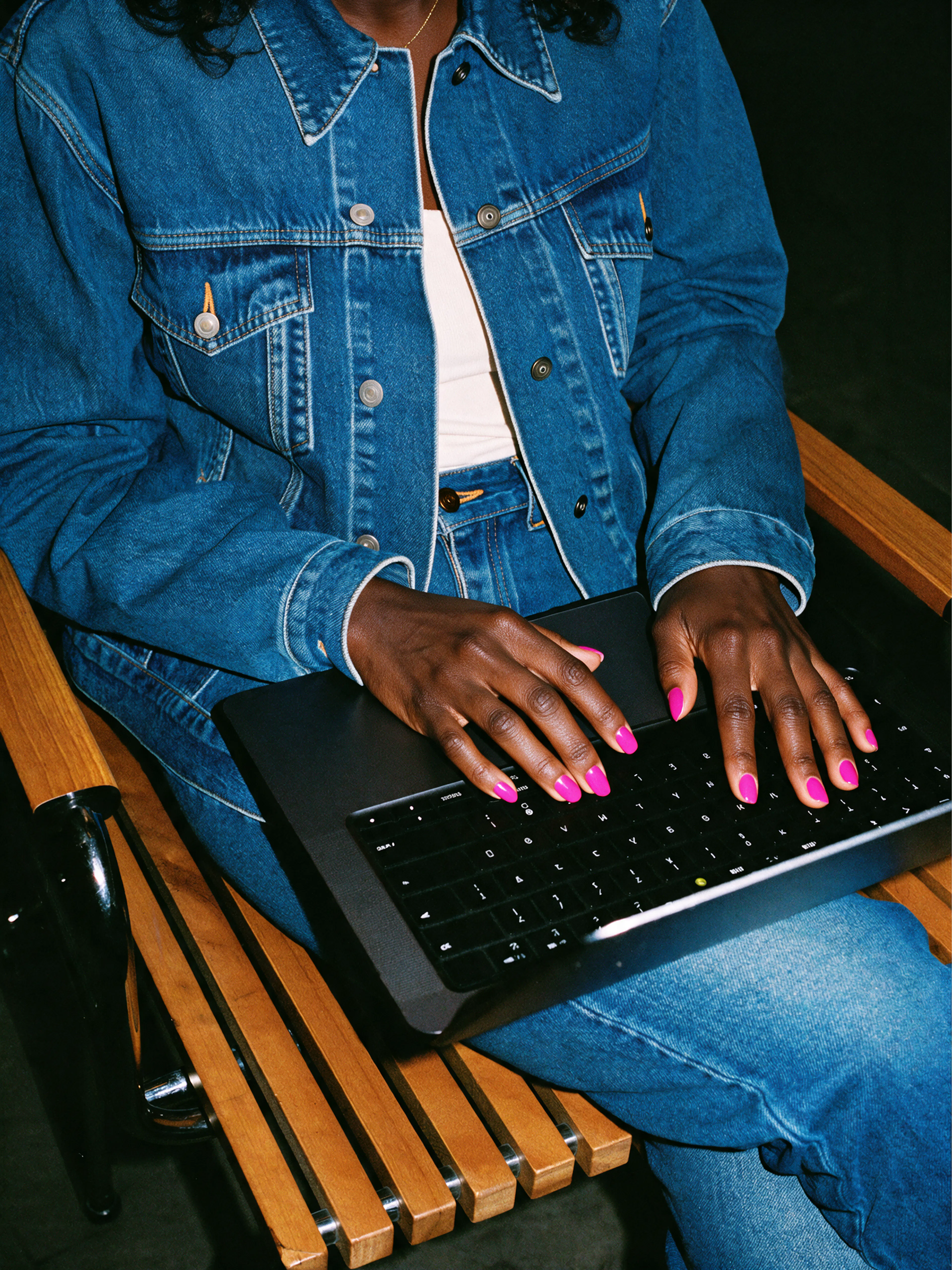 Pink nails typing on laptop keyboard